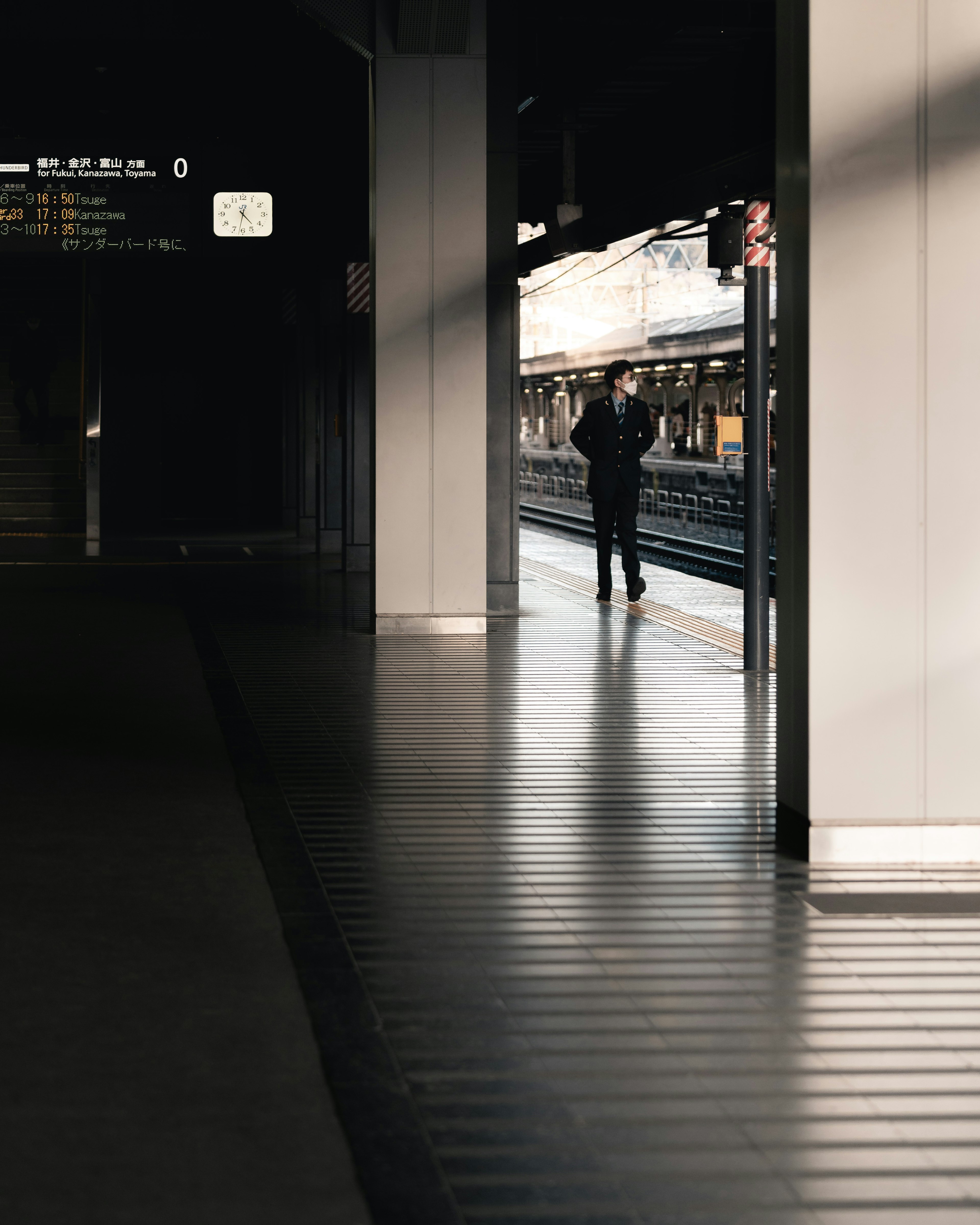 Siluet seseorang berjalan di platform kereta dengan bayangan panjang