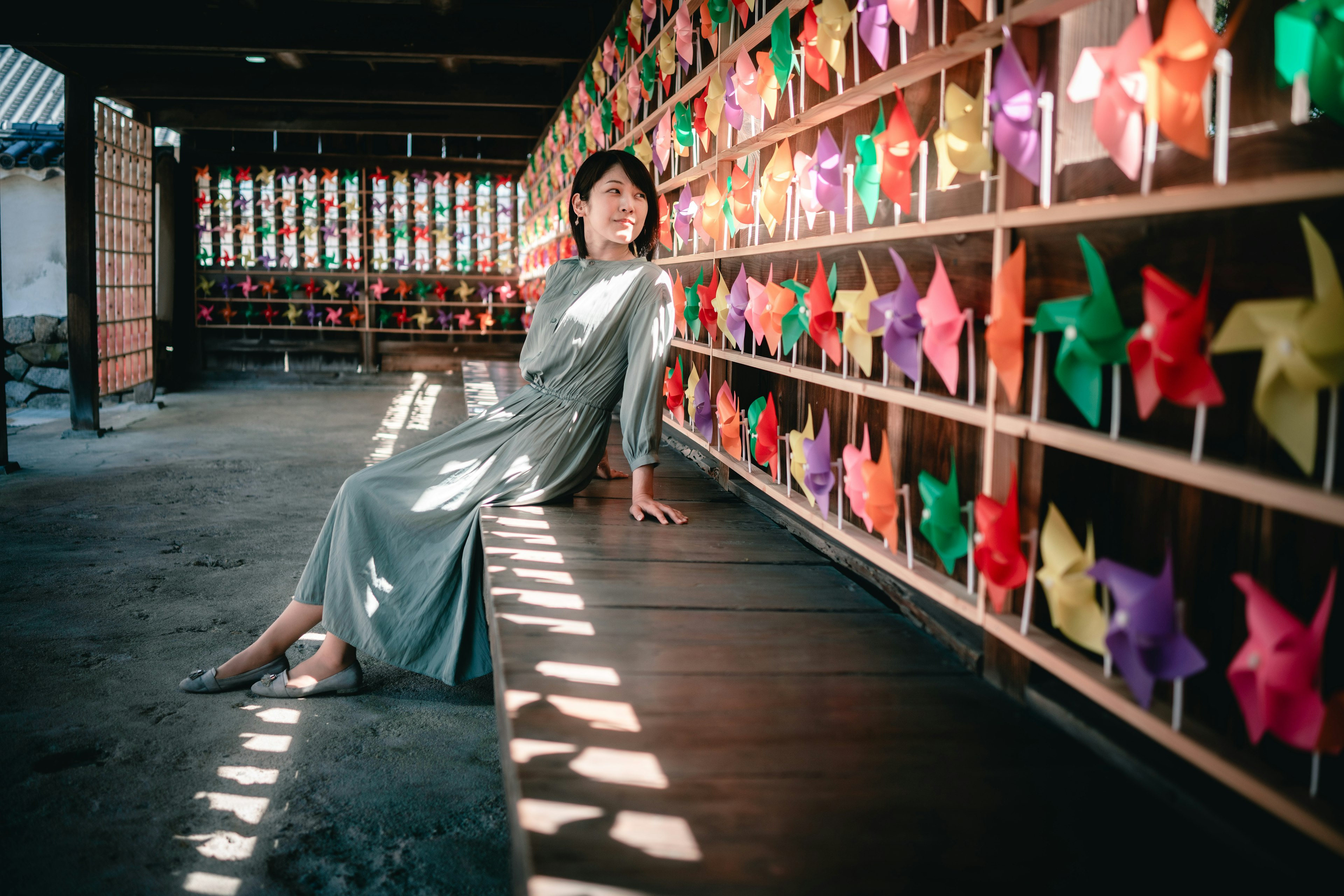 A woman sitting indoors in front of a colorful pinwheel wall