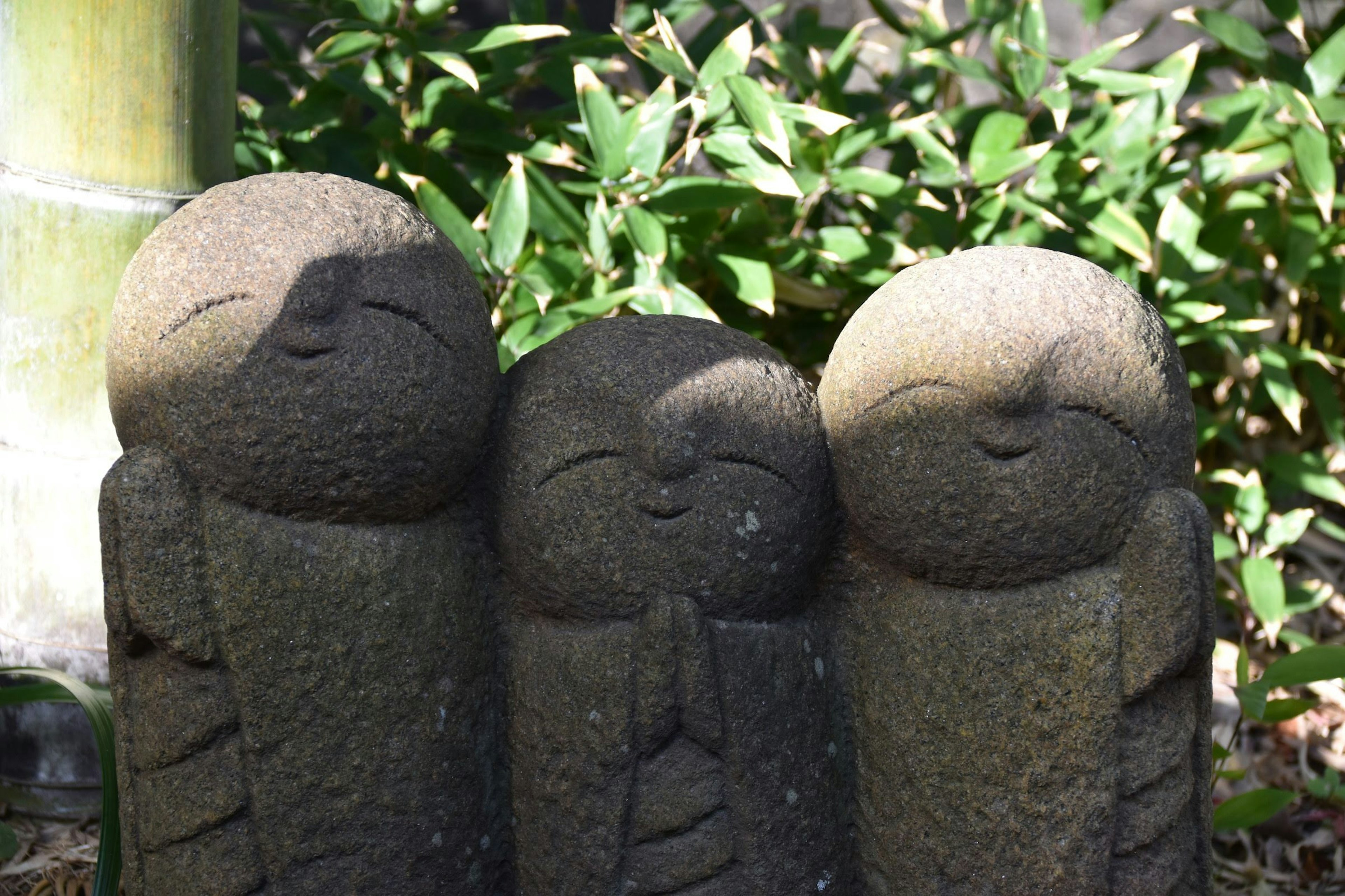 Three stone figures smiling in a green background