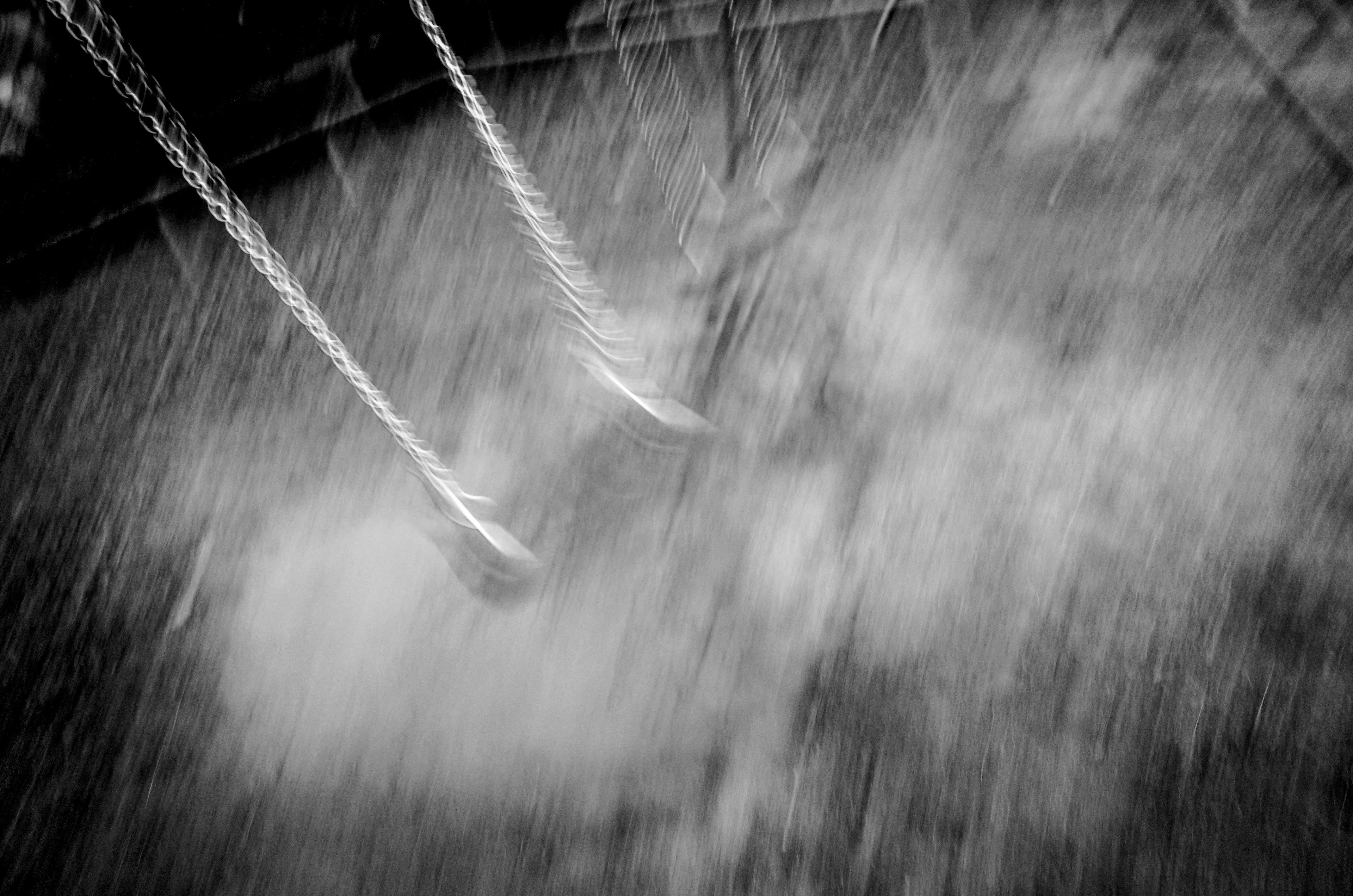 Black and white image of swings with sand below