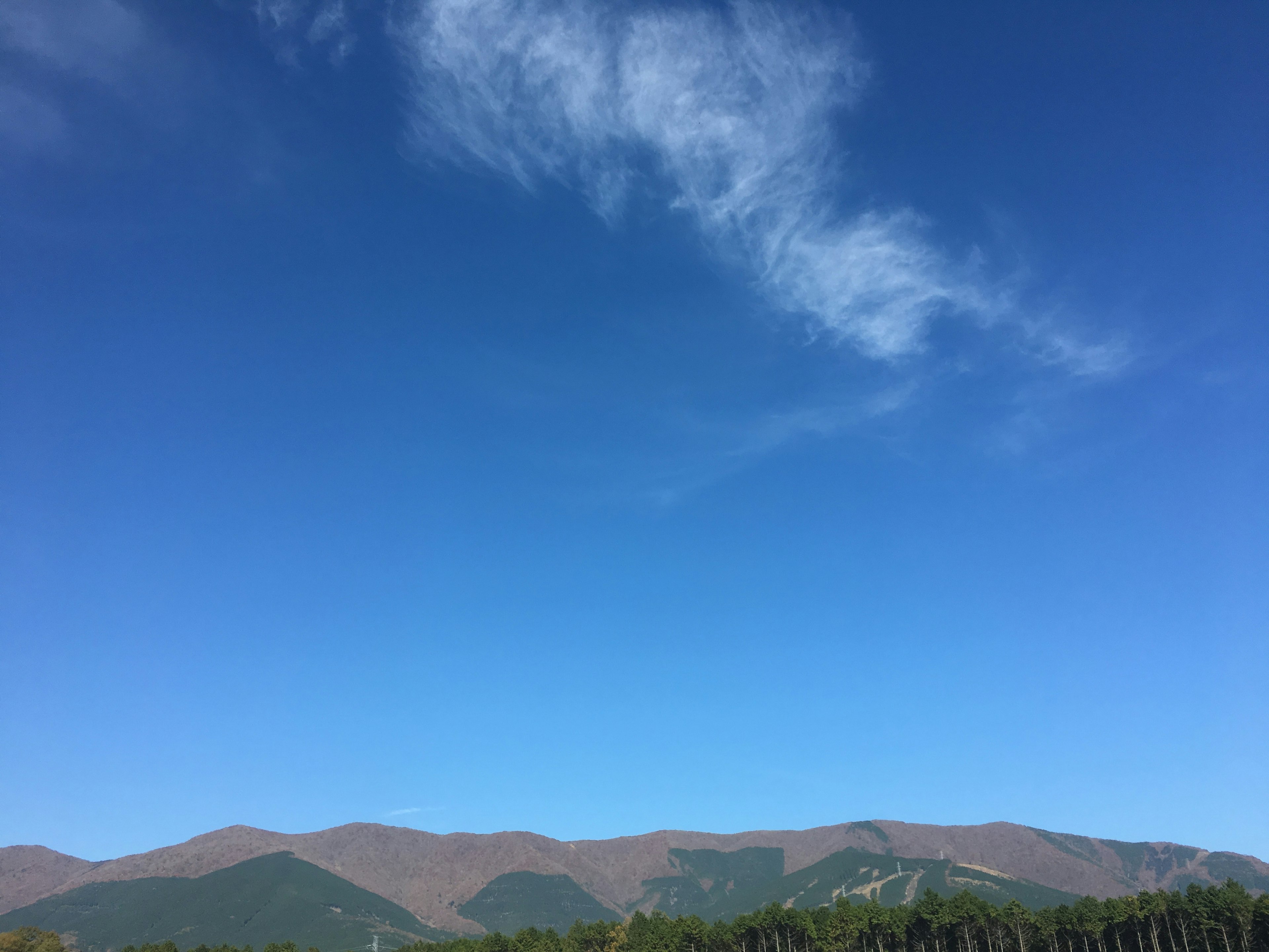 青空と山々が広がる風景で薄い雲が浮かんでいる