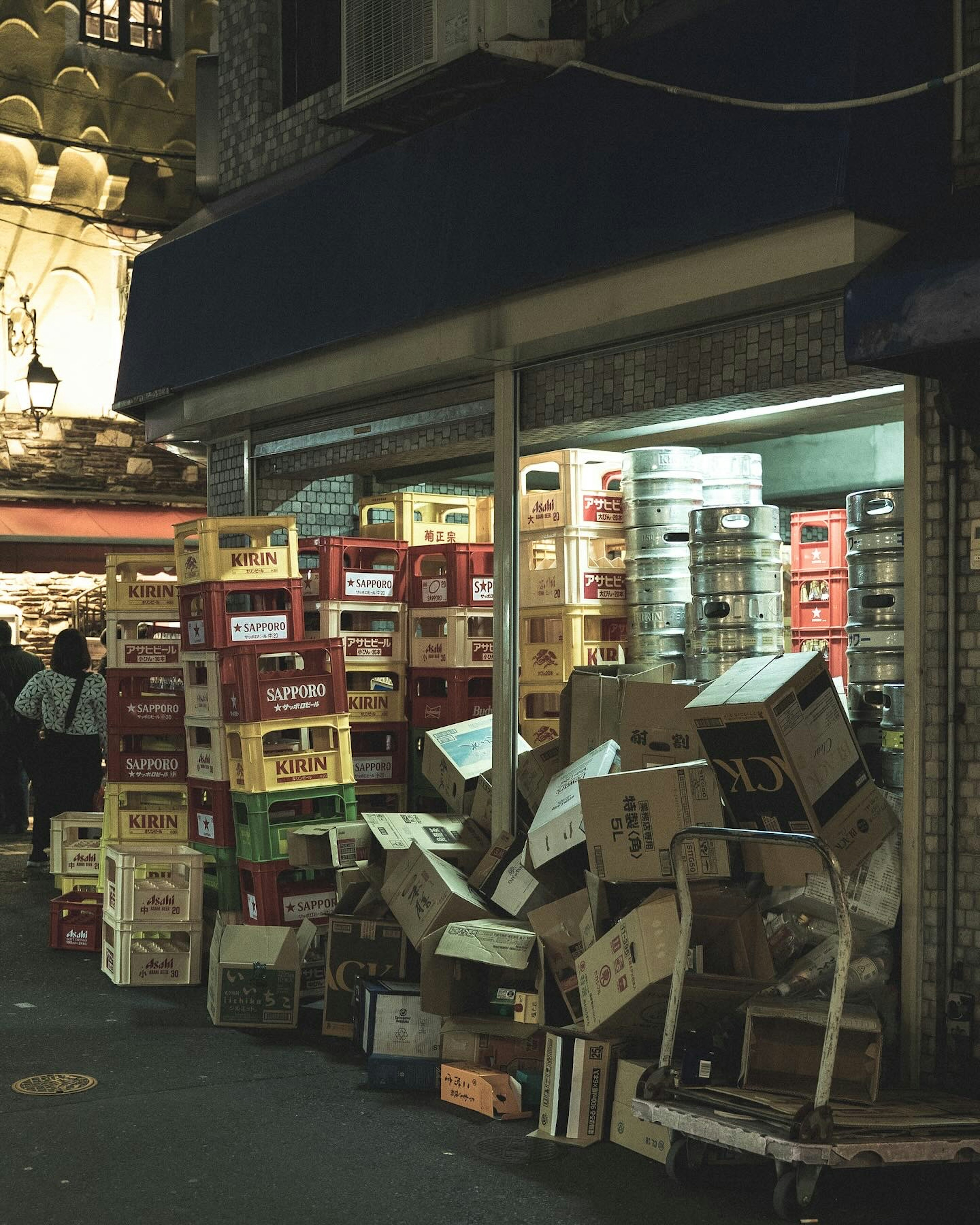 Des boîtes colorées empilées et du carton éparpillé dans une rue faiblement éclairée