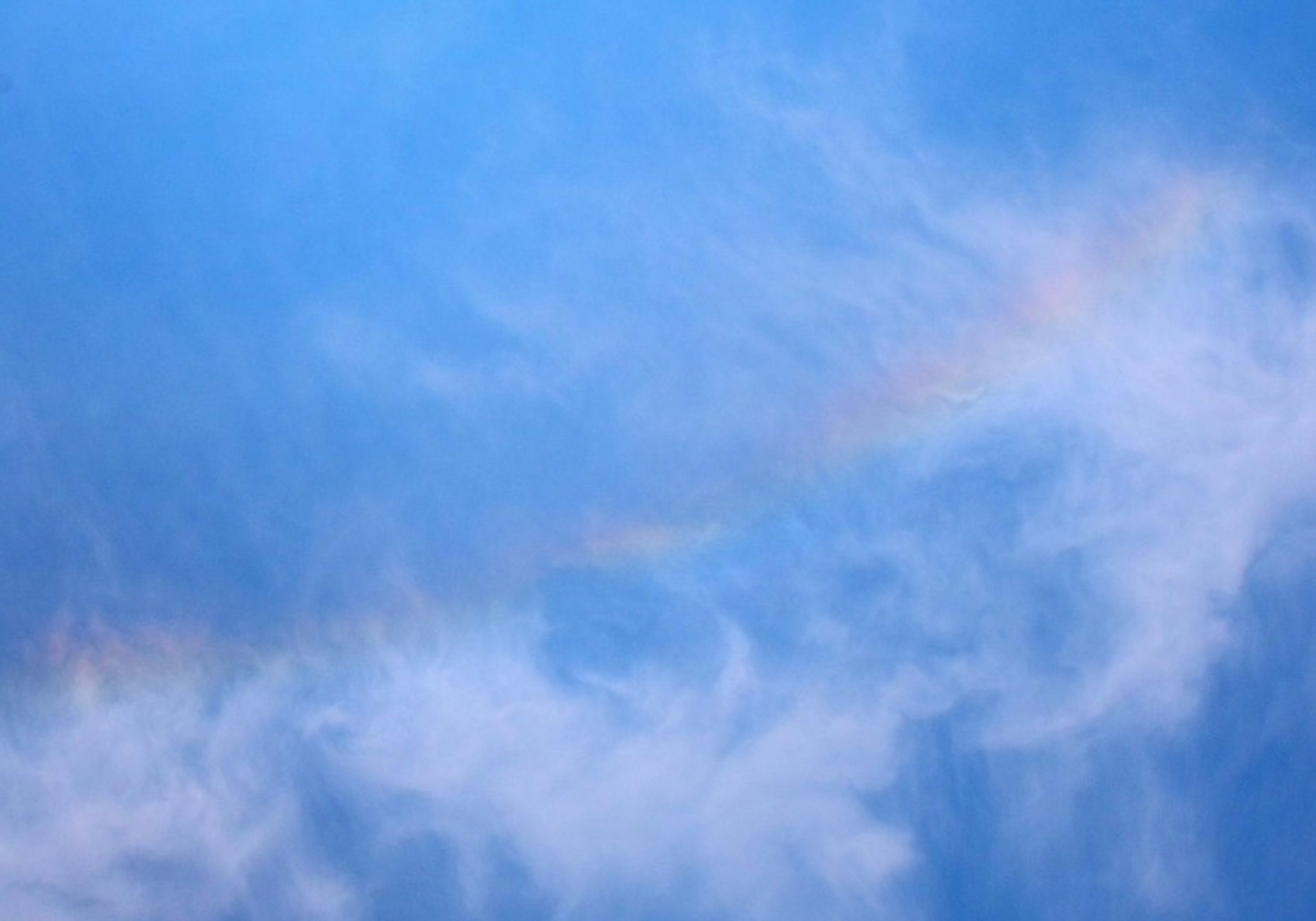 Nuvole leggere con sfumature di arcobaleno in un cielo blu