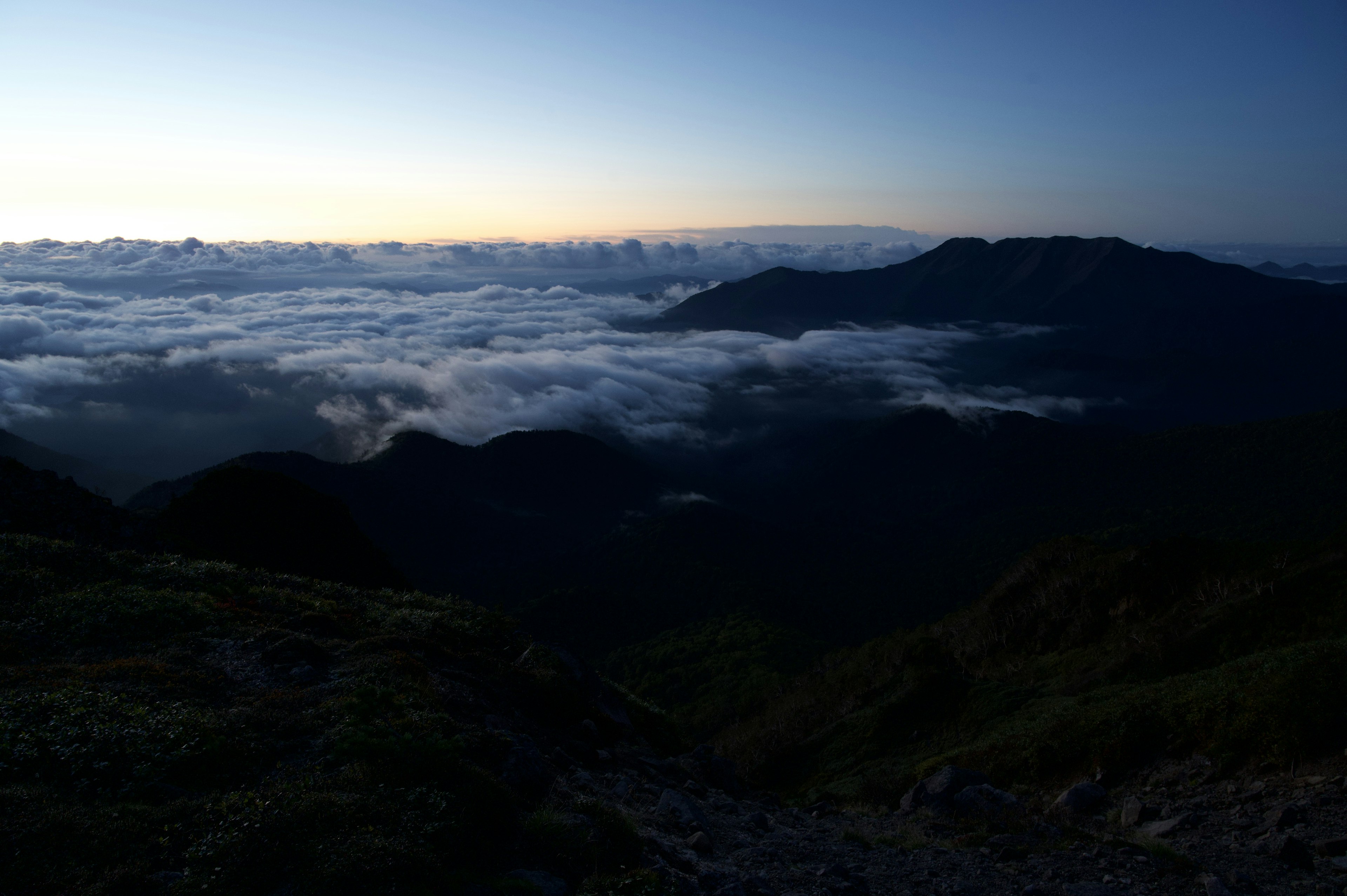 Pemandangan pegunungan dengan lautan awan dan matahari terbenam