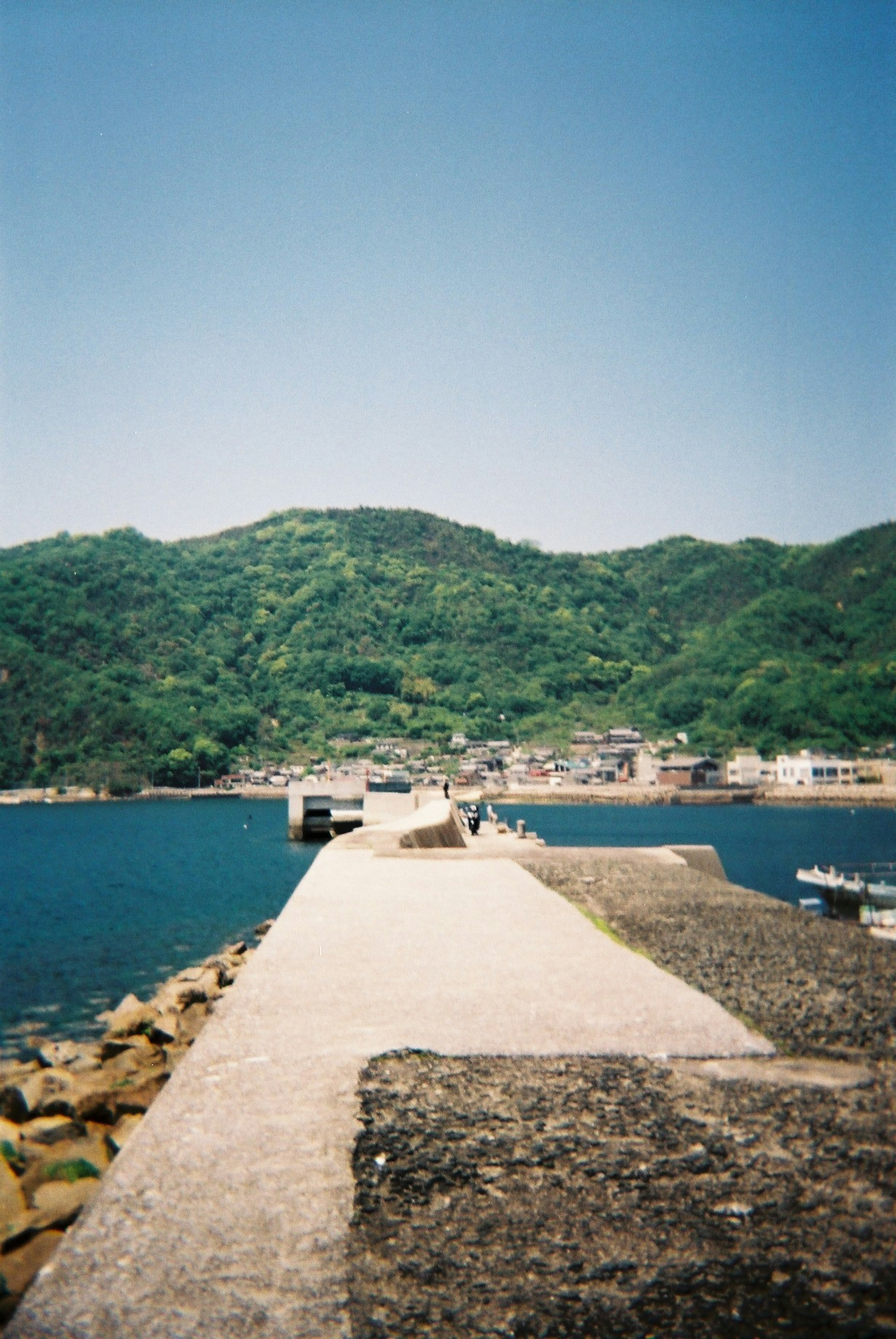 Malersicher Blick auf einen Pier umgeben von blauem Meer und grünen Bergen