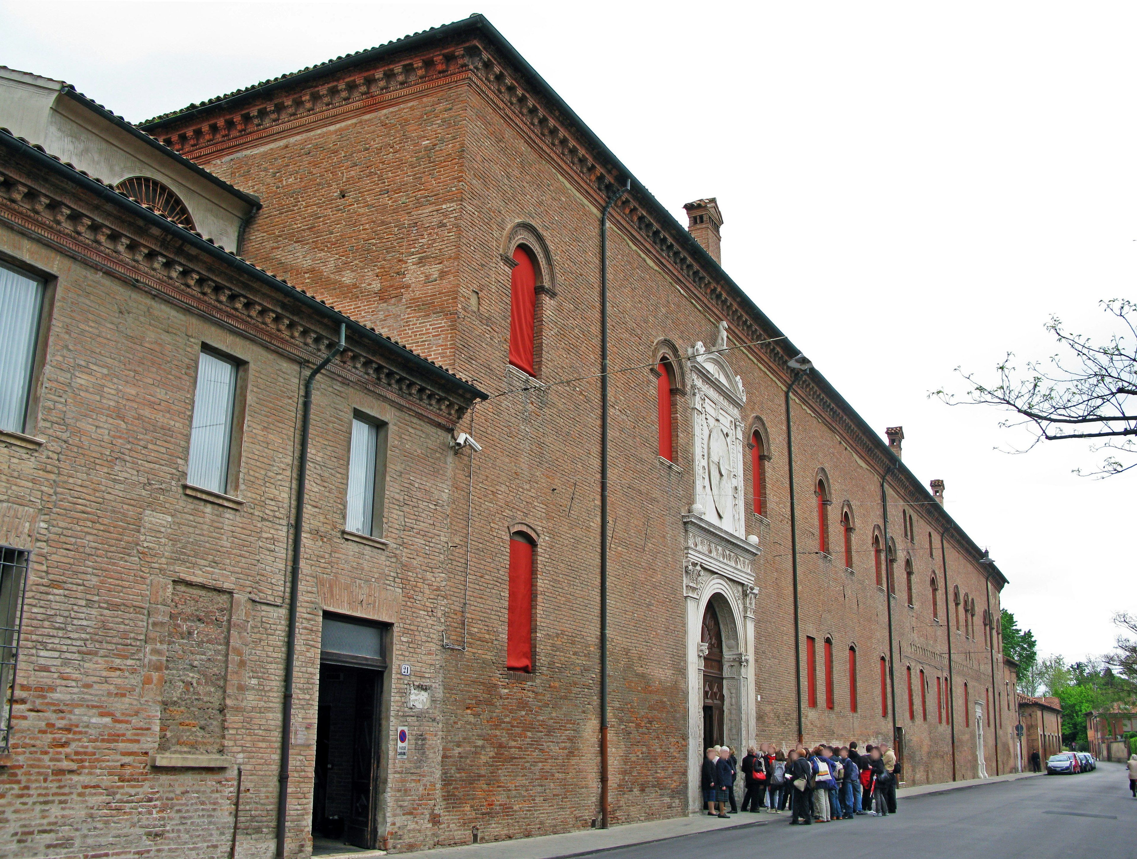 Historic building with red window frames and a group of people