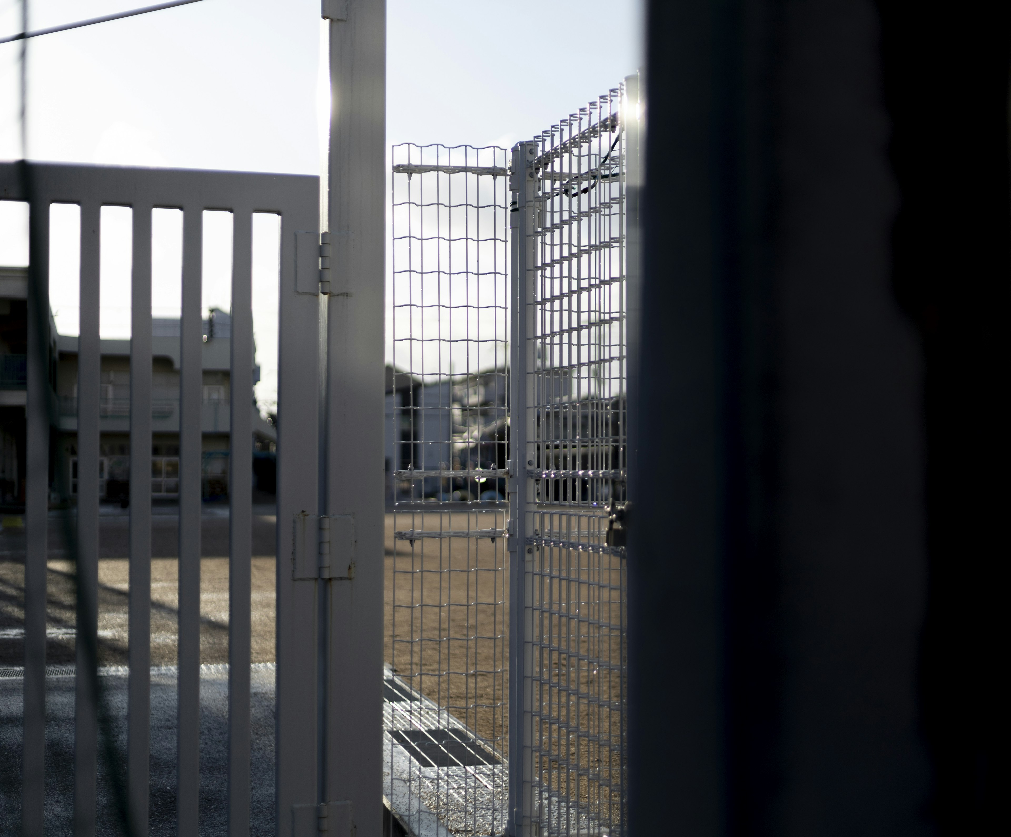 View of an empty lot and buildings beyond a fence