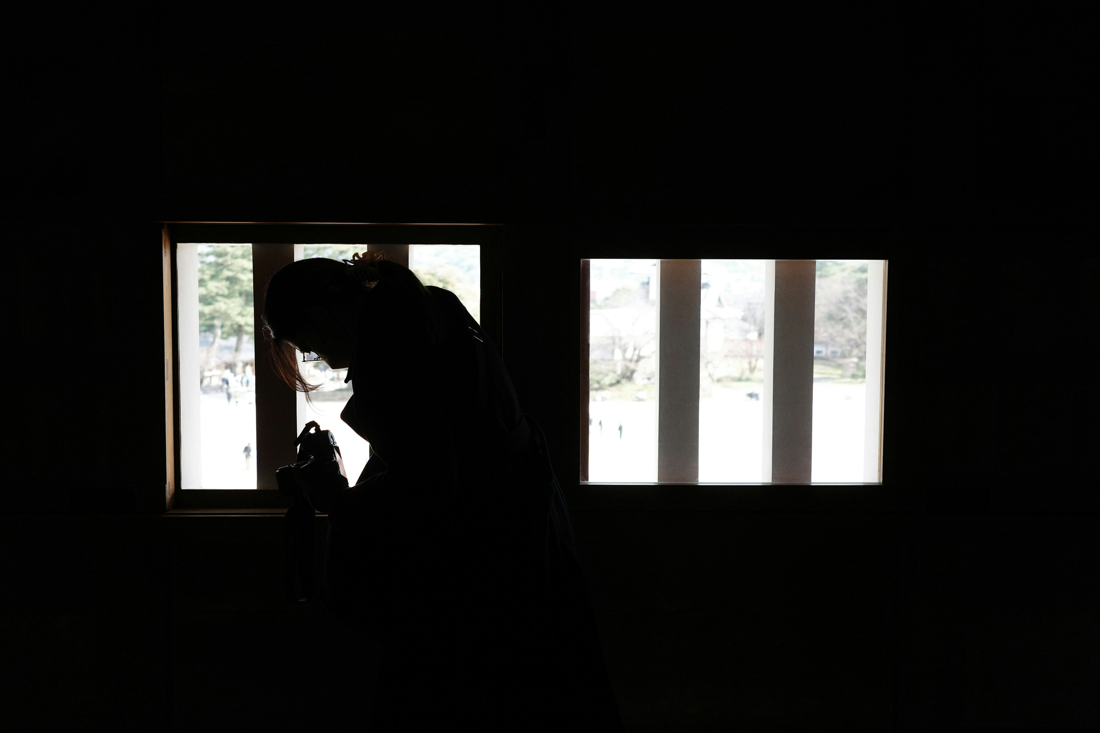 Silhouette einer Person, die durch ein Fenster in einem dunklen Raum schaut