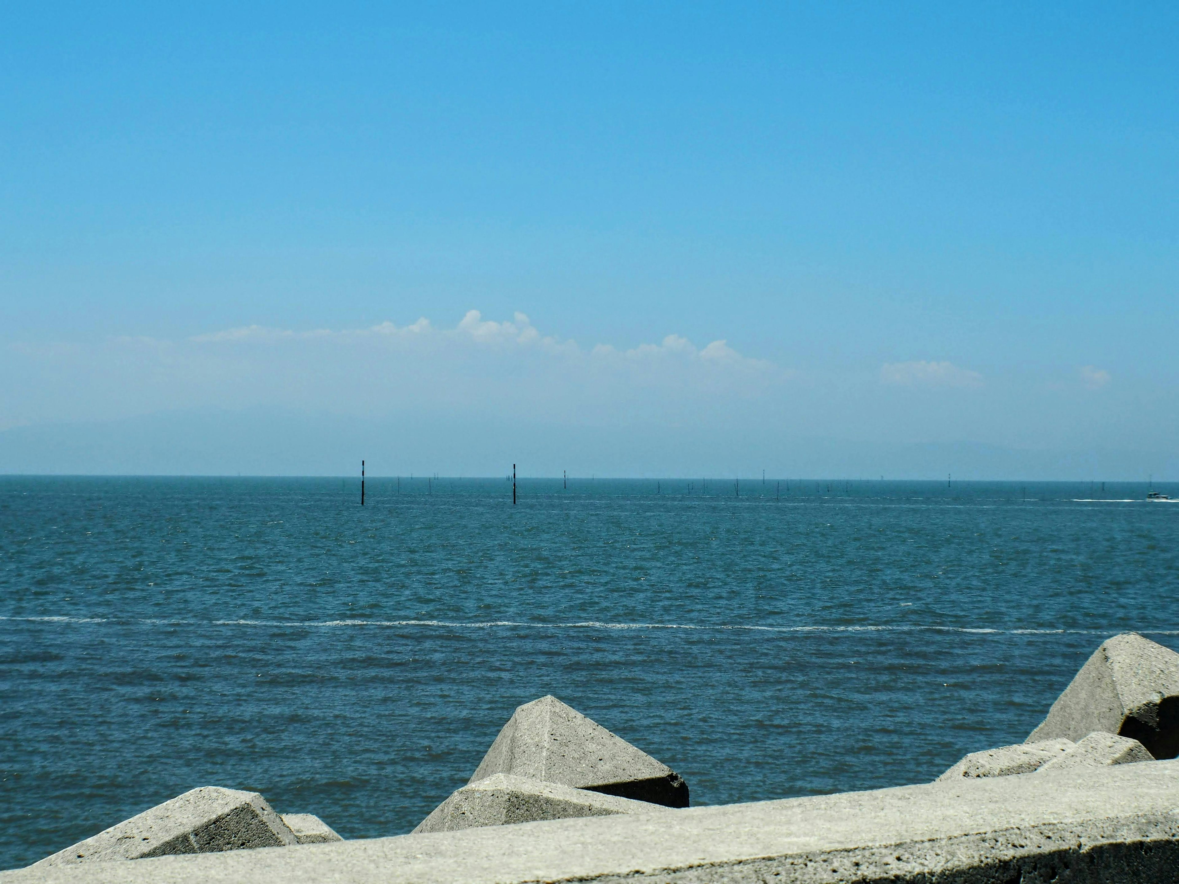 Molo in cemento lungo un paesaggio marino con cielo blu e oceano