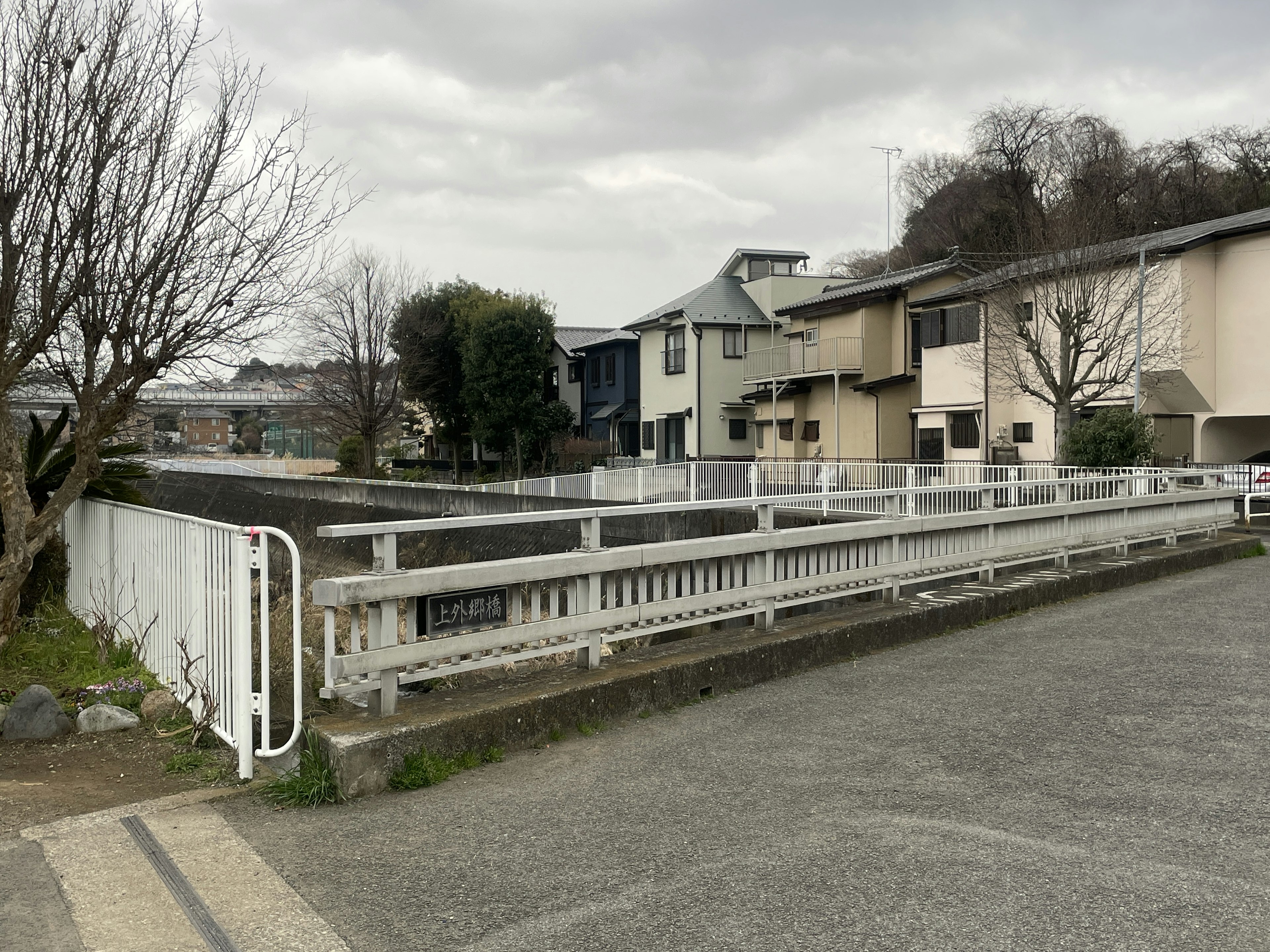 Quiet street scene with white fence and residential buildings