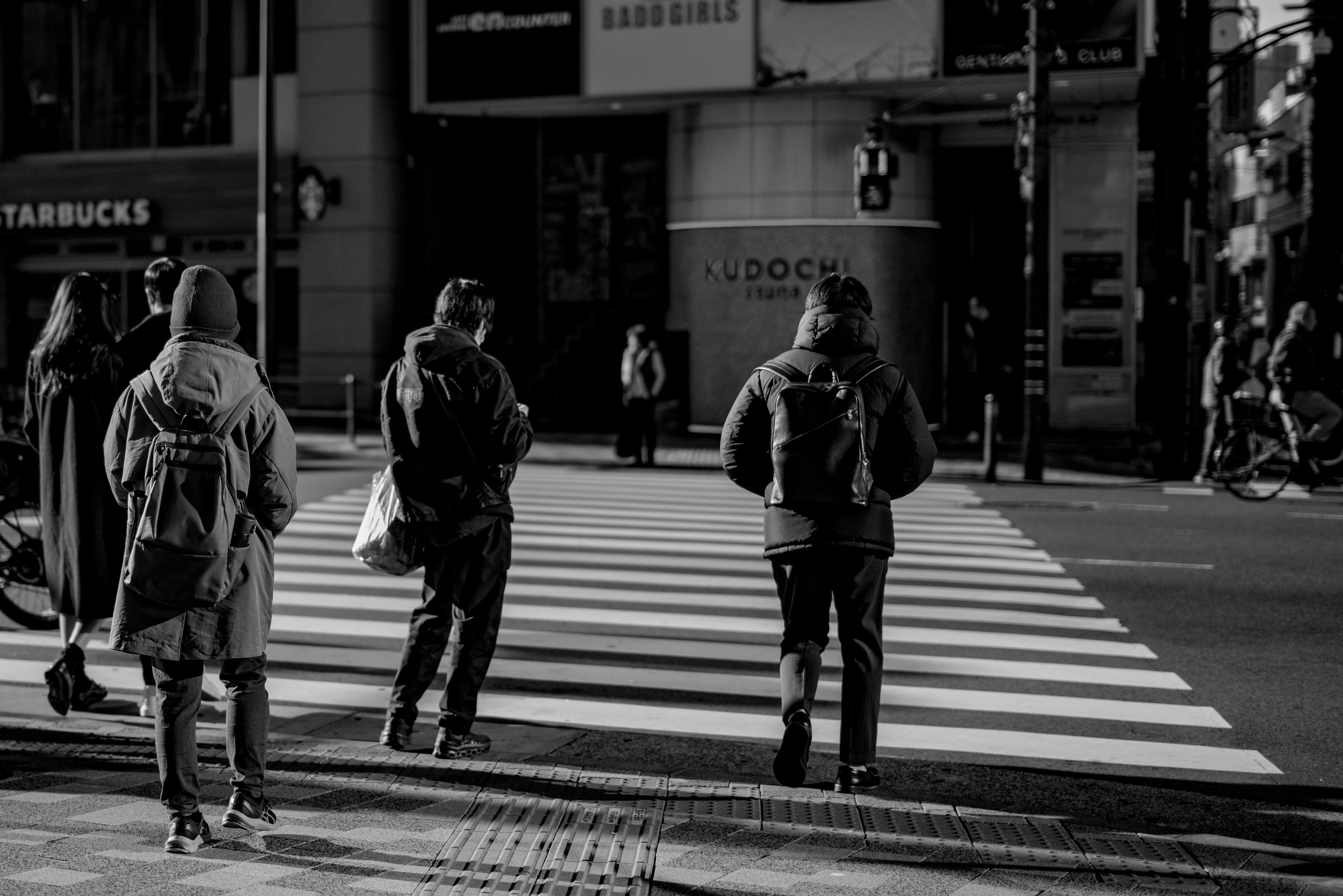 白黒の街角で横断歩道を渡る人々とスターバックスの店舗