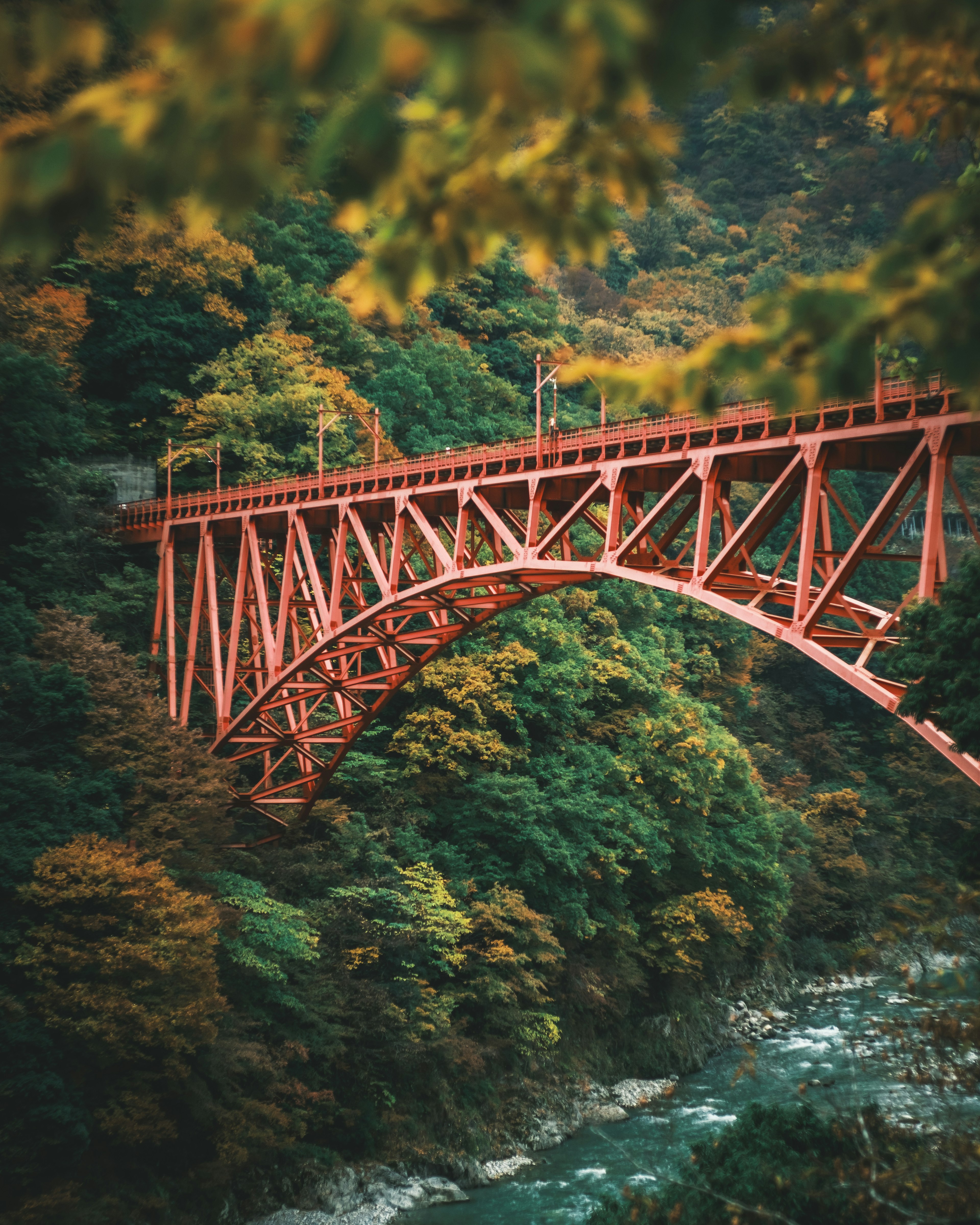 A vibrant red bridge arching over a lush green landscape