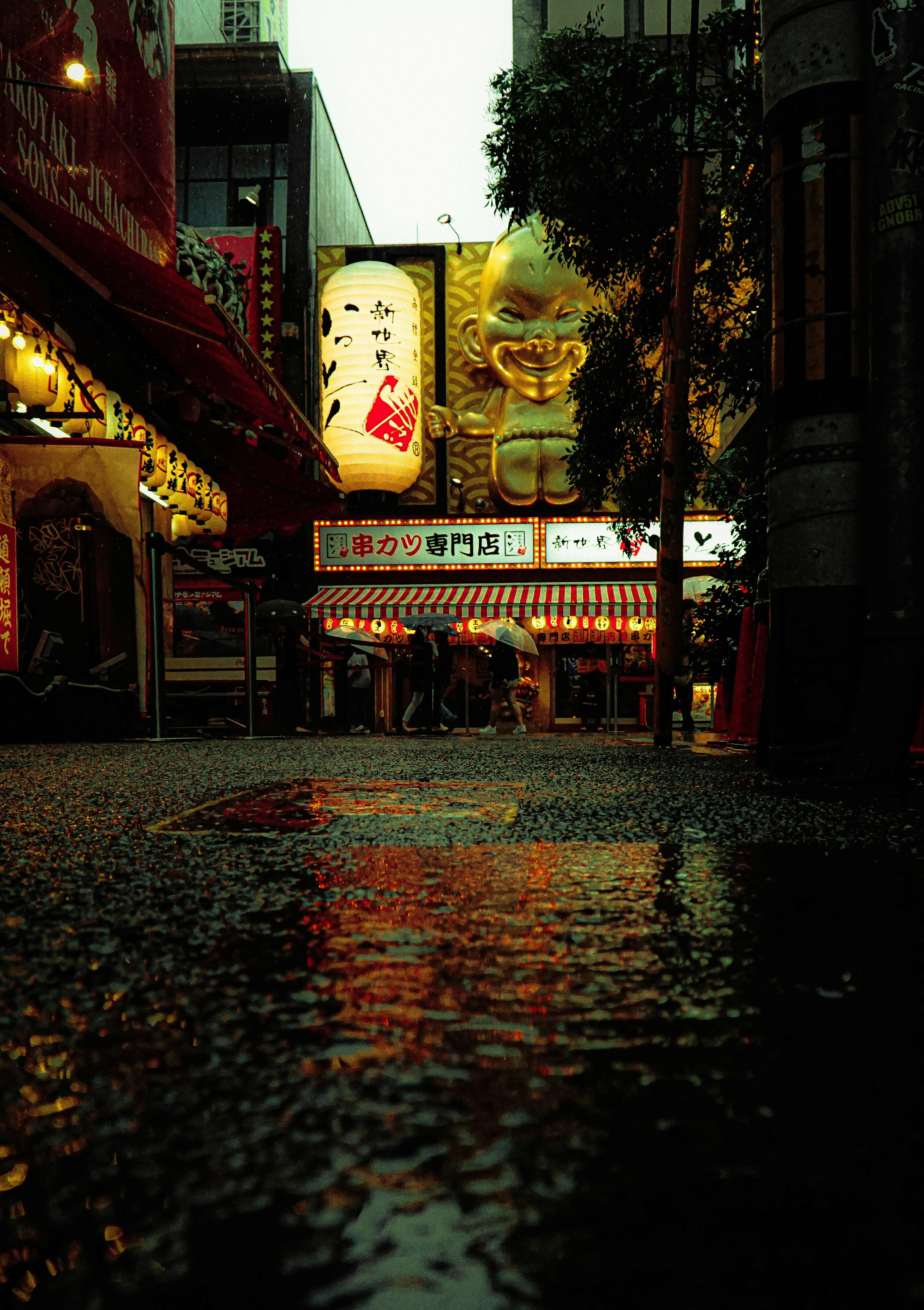 Vue de rue réfléchissant la pluie avec un grand panneau de chat porte-bonheur et des lumières néon la nuit