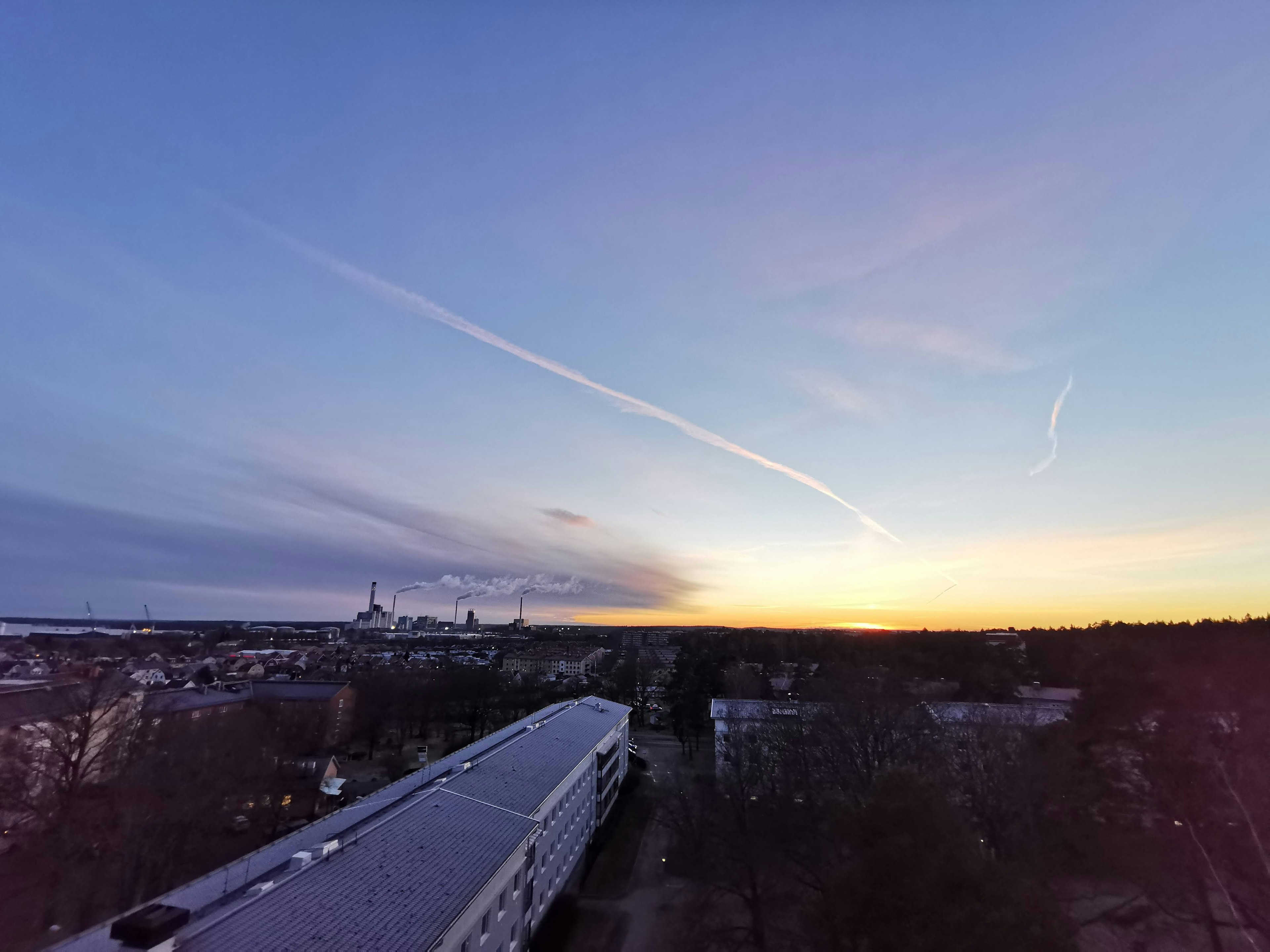 Sonnenuntergangslandschaft mit buntem Himmel und entferntem Stadthorizont