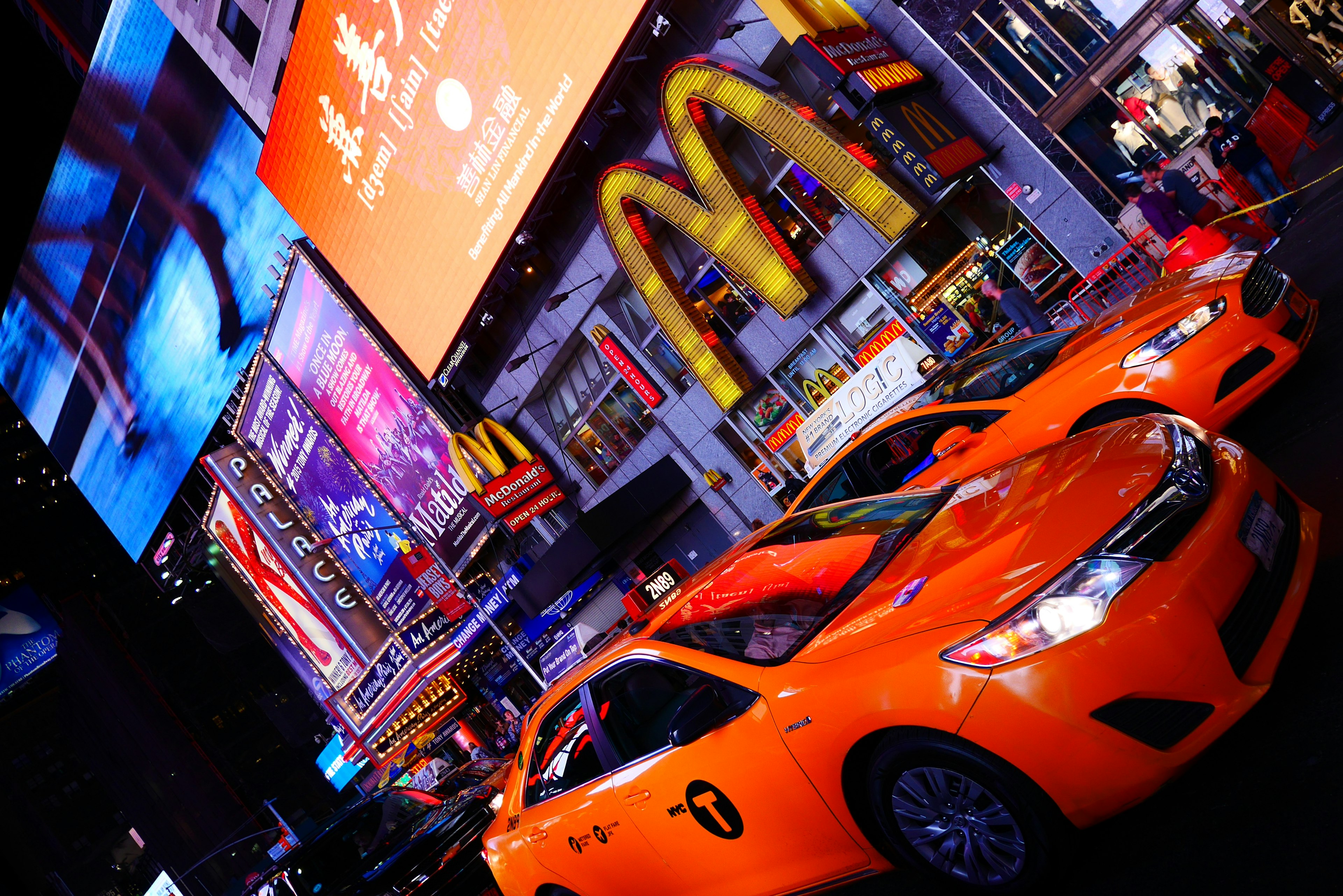 Taksi oranye di Times Square yang diterangi di malam hari dengan iklan yang cerah