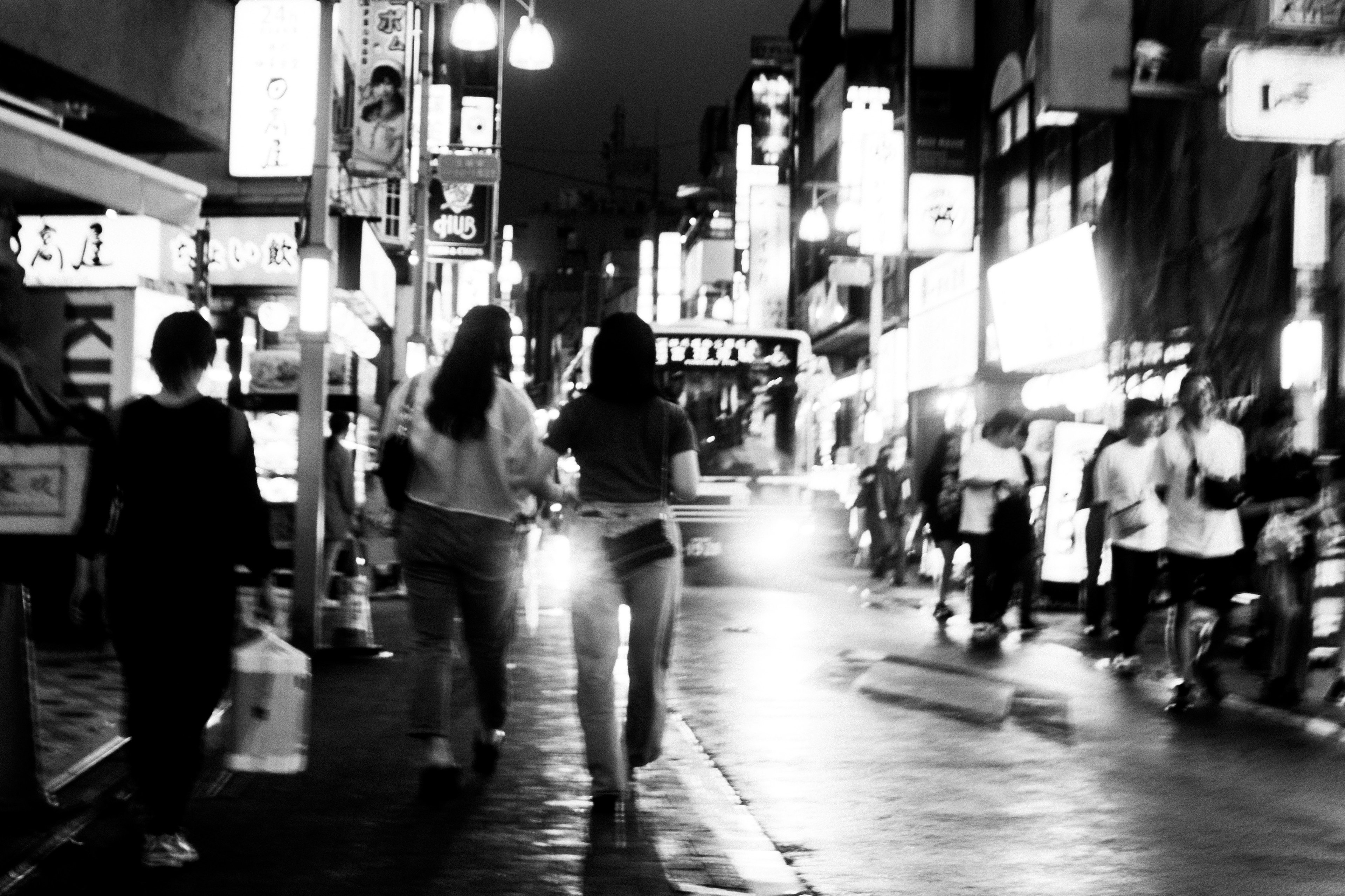 Two women walking in a nighttime street with bright signs