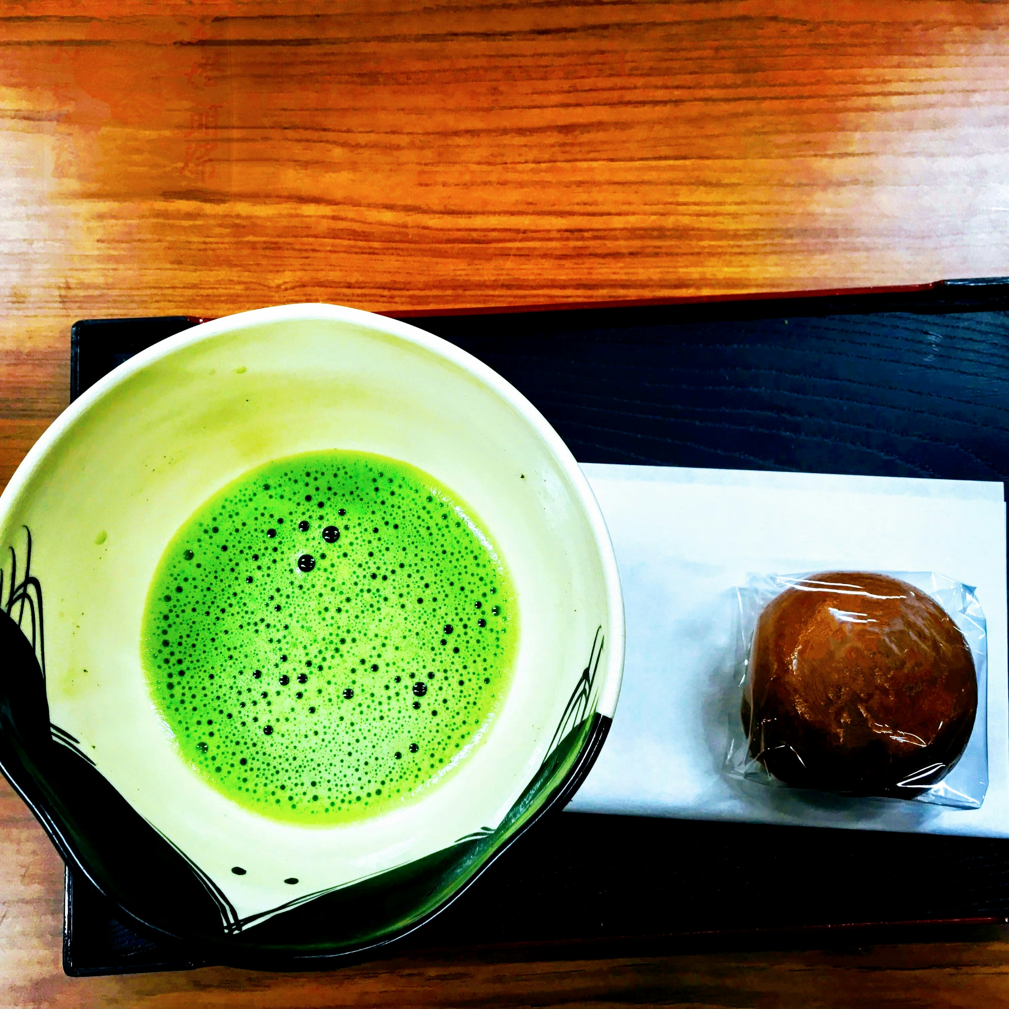 Sebuah mangkuk teh matcha di samping kue Jepang