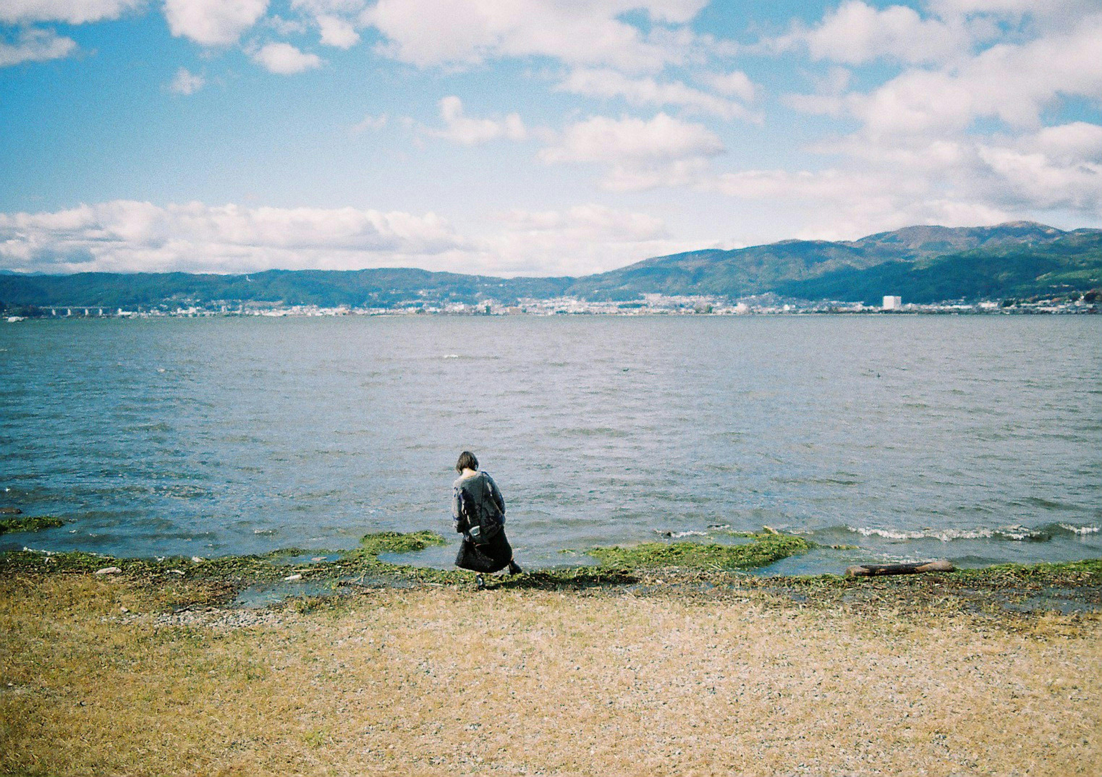 Person sitzt ruhig am Strand mit blauem Himmel