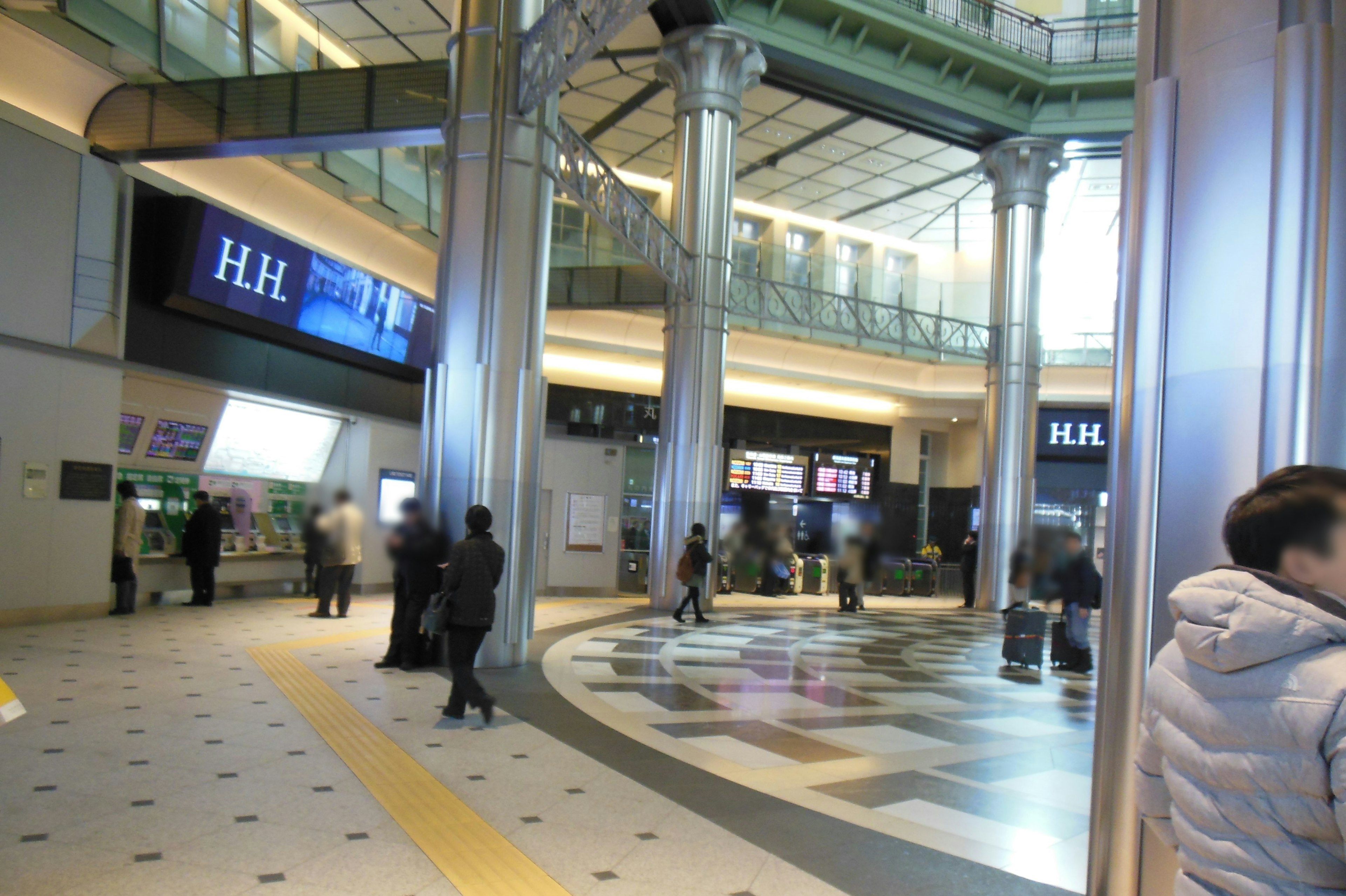 Interno spazioso di una stazione ferroviaria con molte persone e colonne distintive