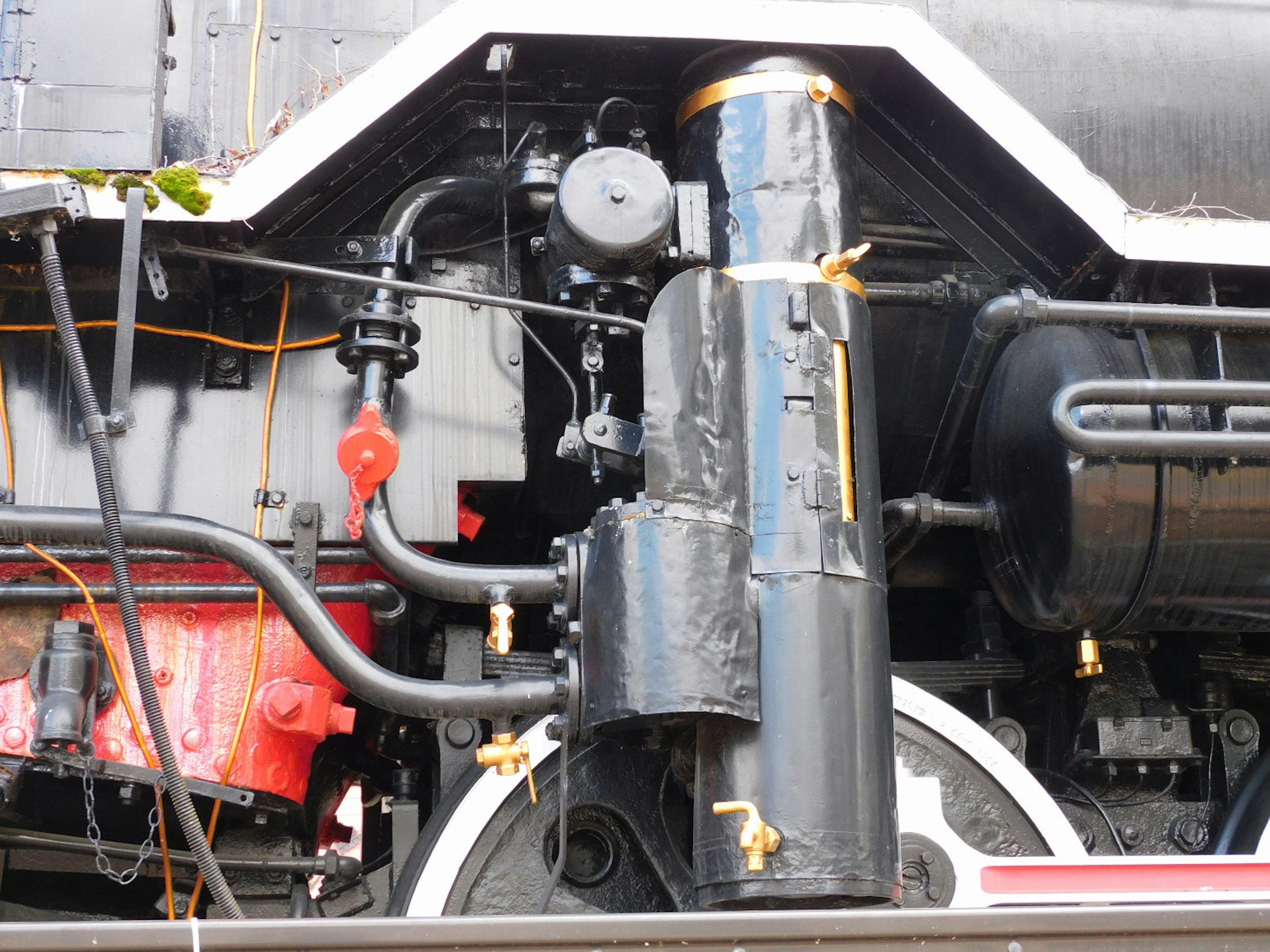 Primo piano della meccanica di una locomotiva a vapore con un cilindro nero e tubi