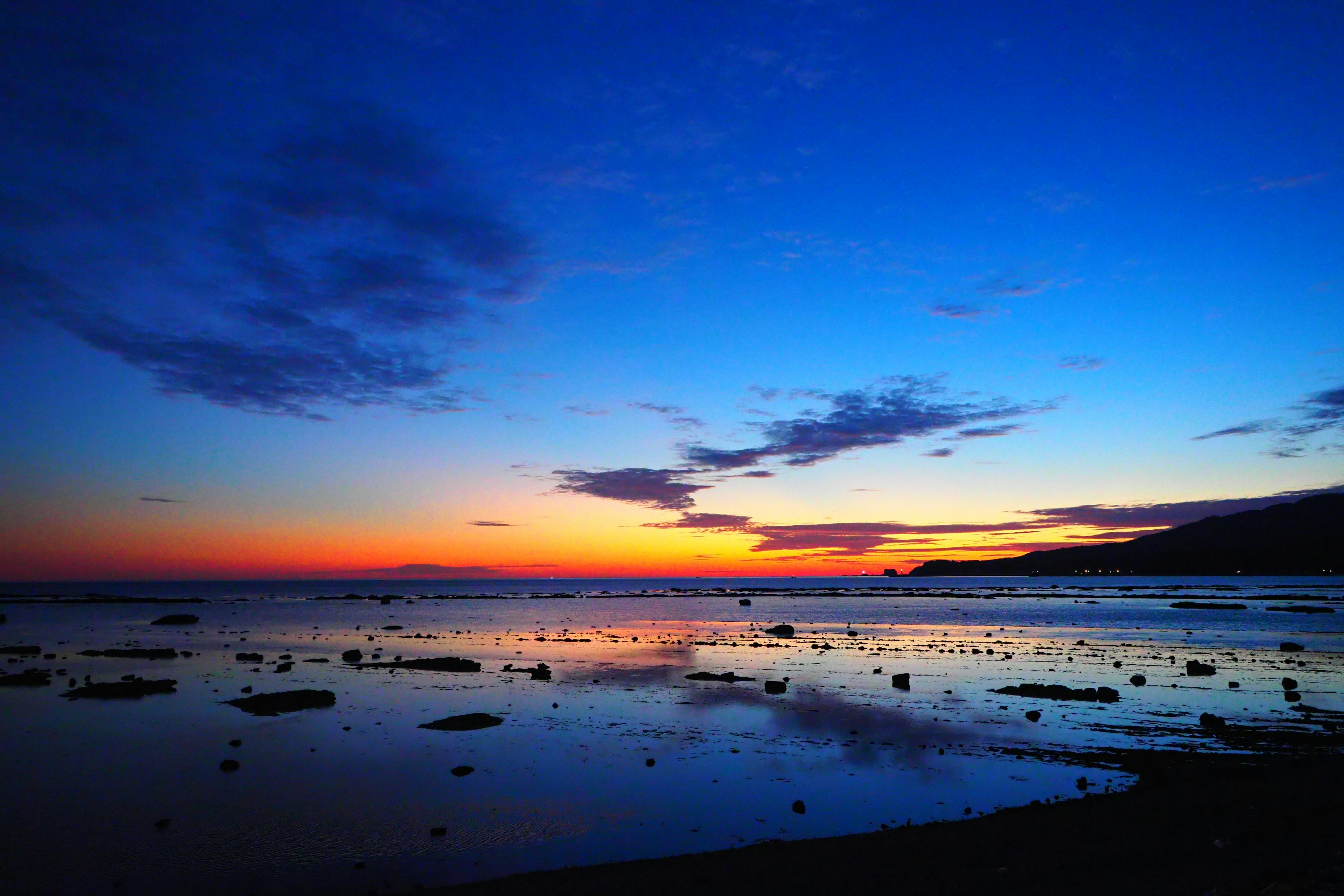 Scène de coucher de soleil côtier avec un ciel bleu et un coucher de soleil orange