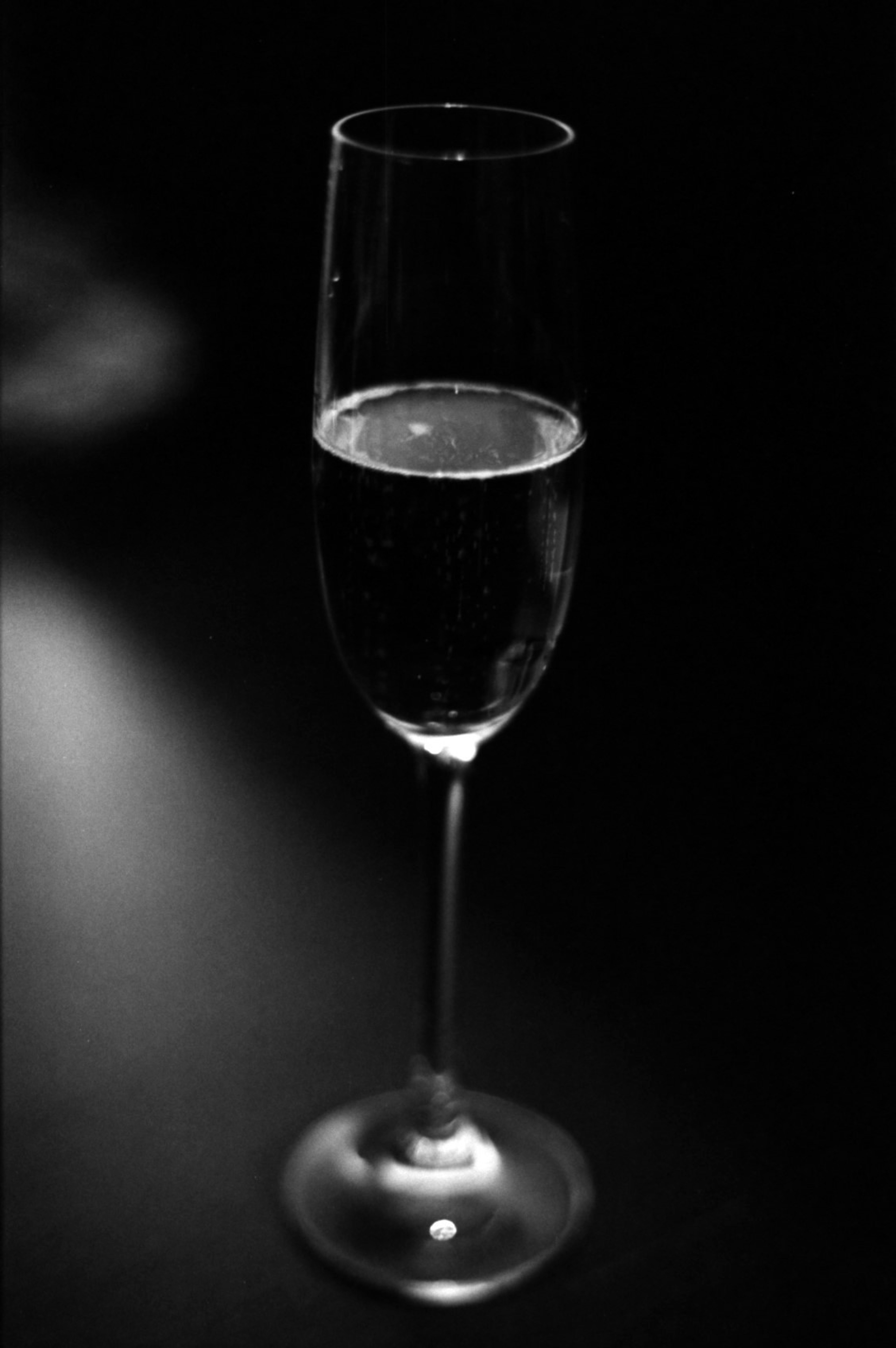 Photographie d'un verre à champagne se tenant contre un fond noir