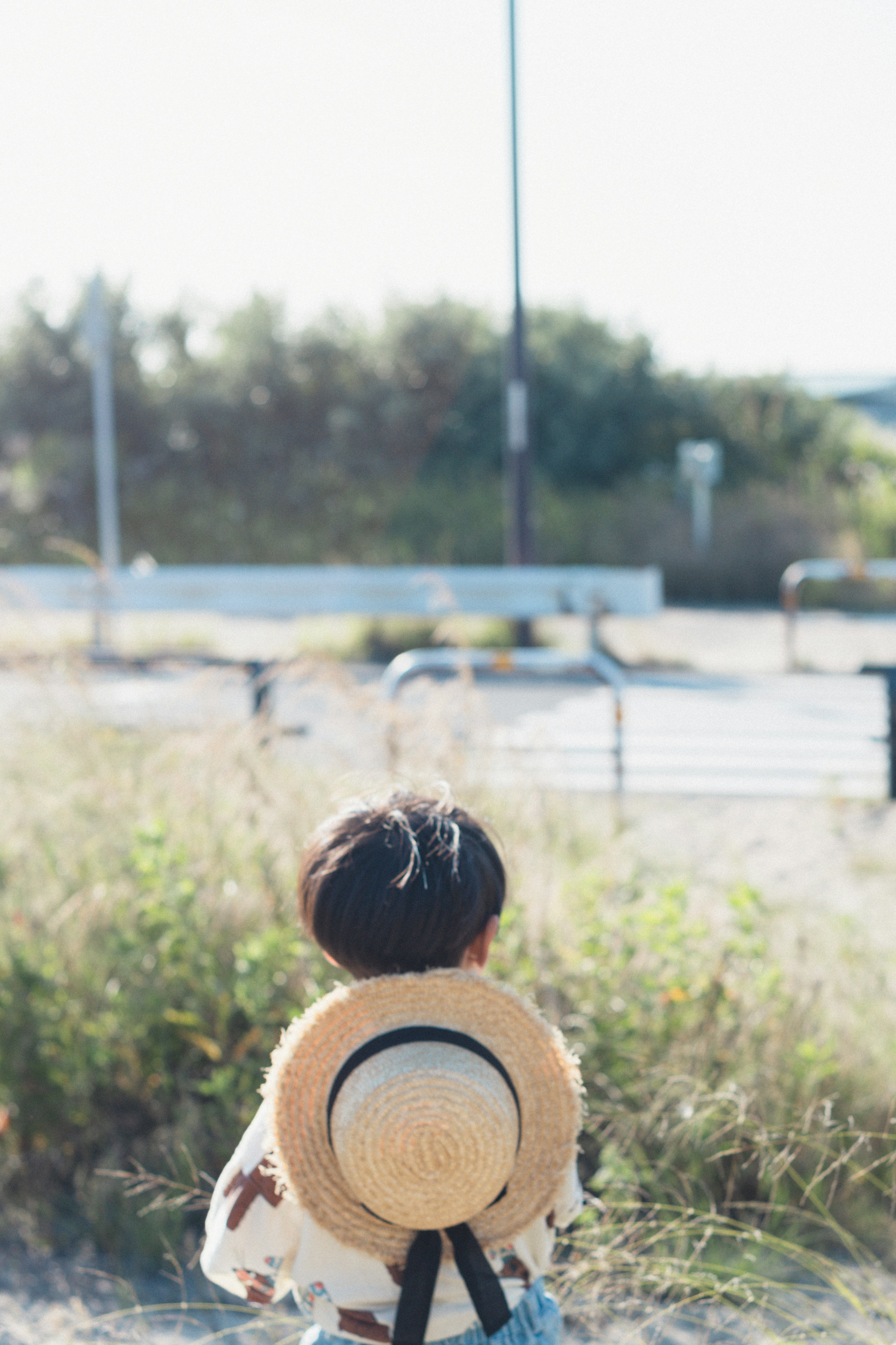 Un bambino con un cappello di paglia in piedi nella natura con uno sfondo sereno