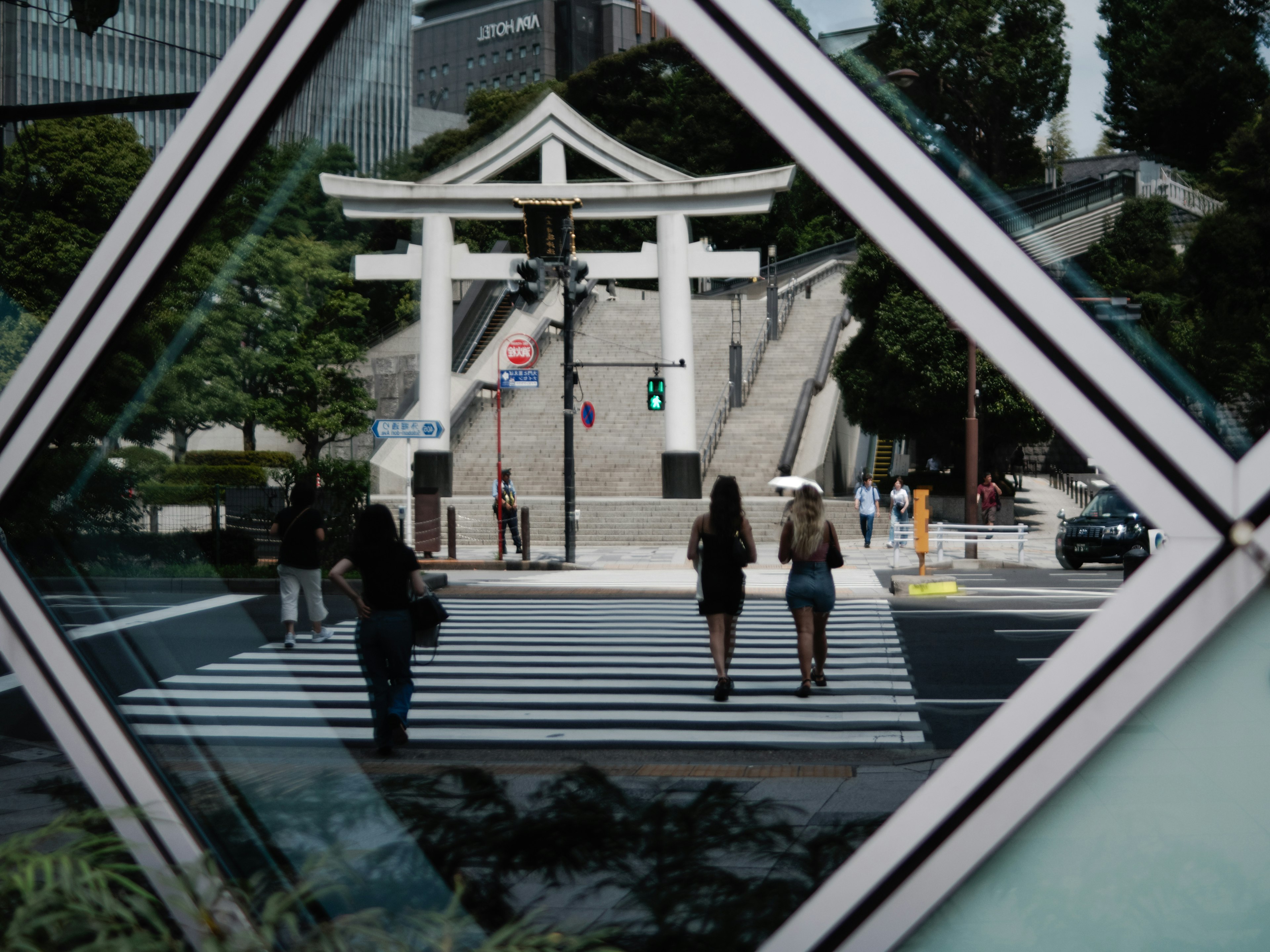 Hai người phụ nữ băng qua đường với cổng torii ở phía sau