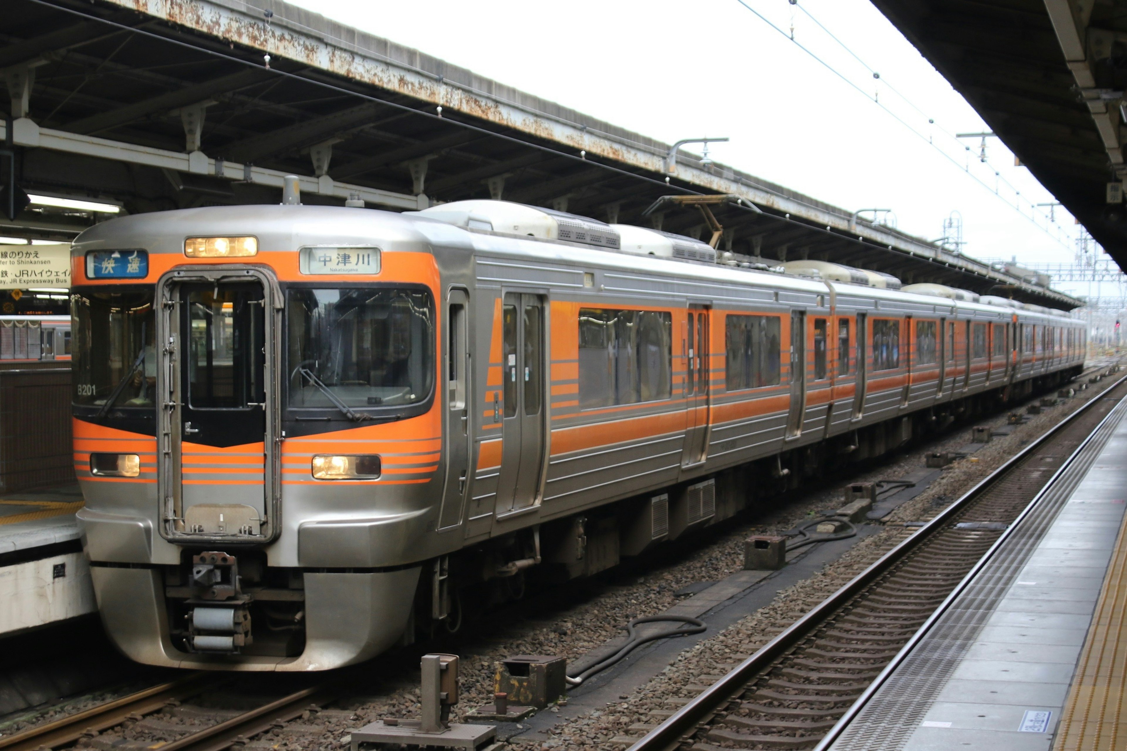 Ein orange-silberner Zug hält am Bahnhof