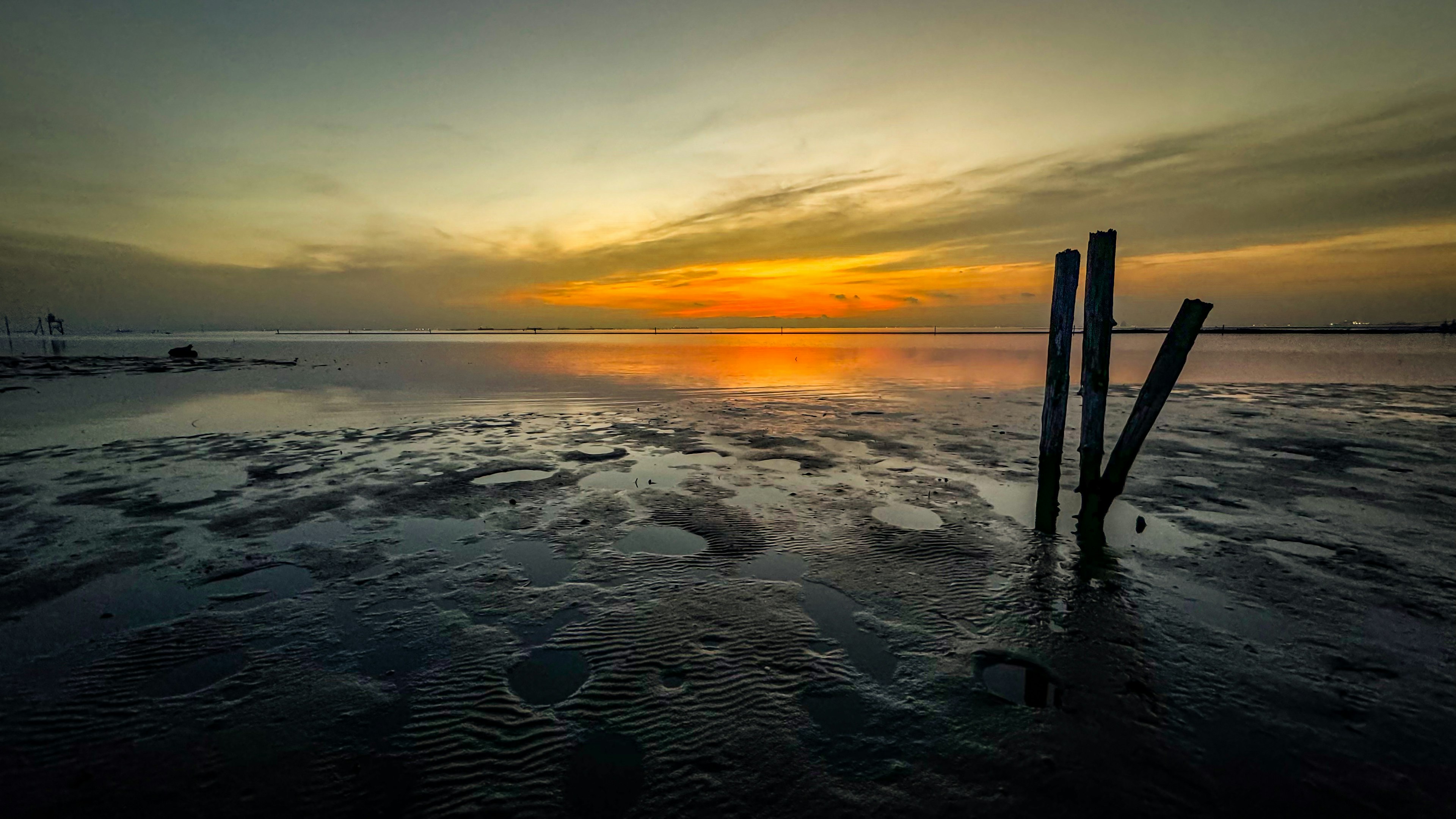 Scenic sunset over the ocean with wooden posts