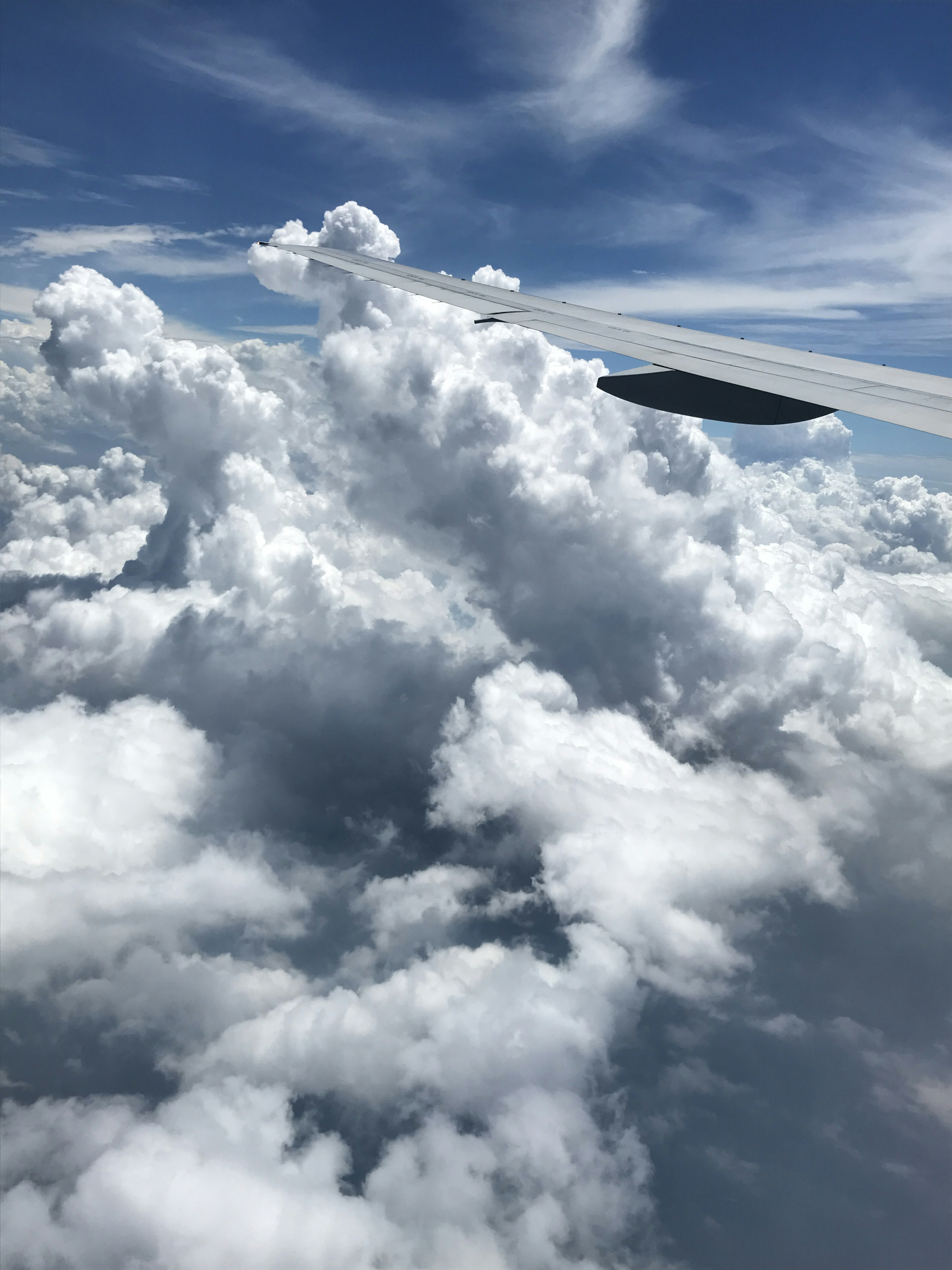 Blick auf einen Flugzeugflügel über flauschigen weißen Wolken unter einem blauen Himmel