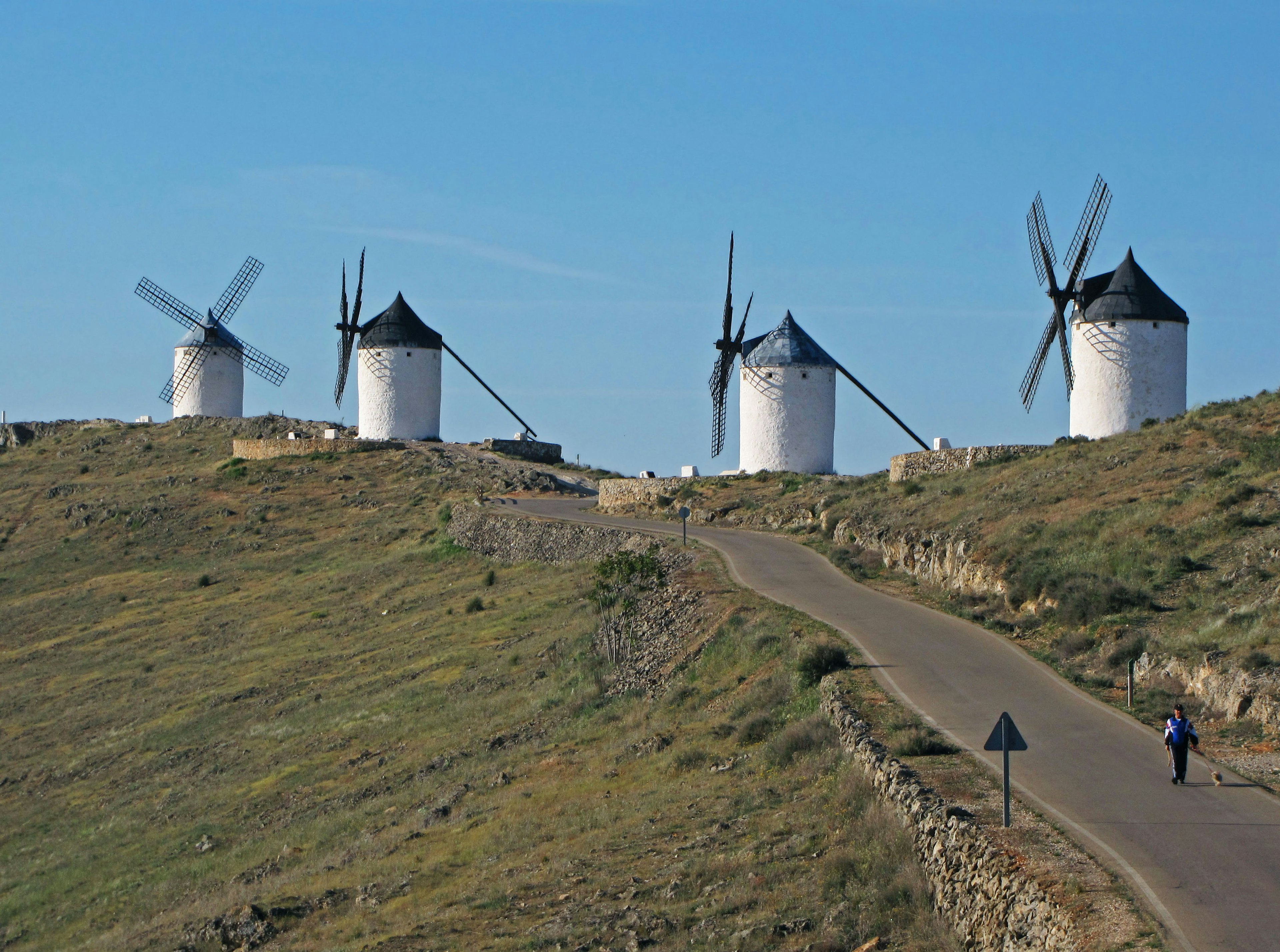 Landschaft mit Windmühlen unter klarem Himmel eine Person, die auf einer Straße geht