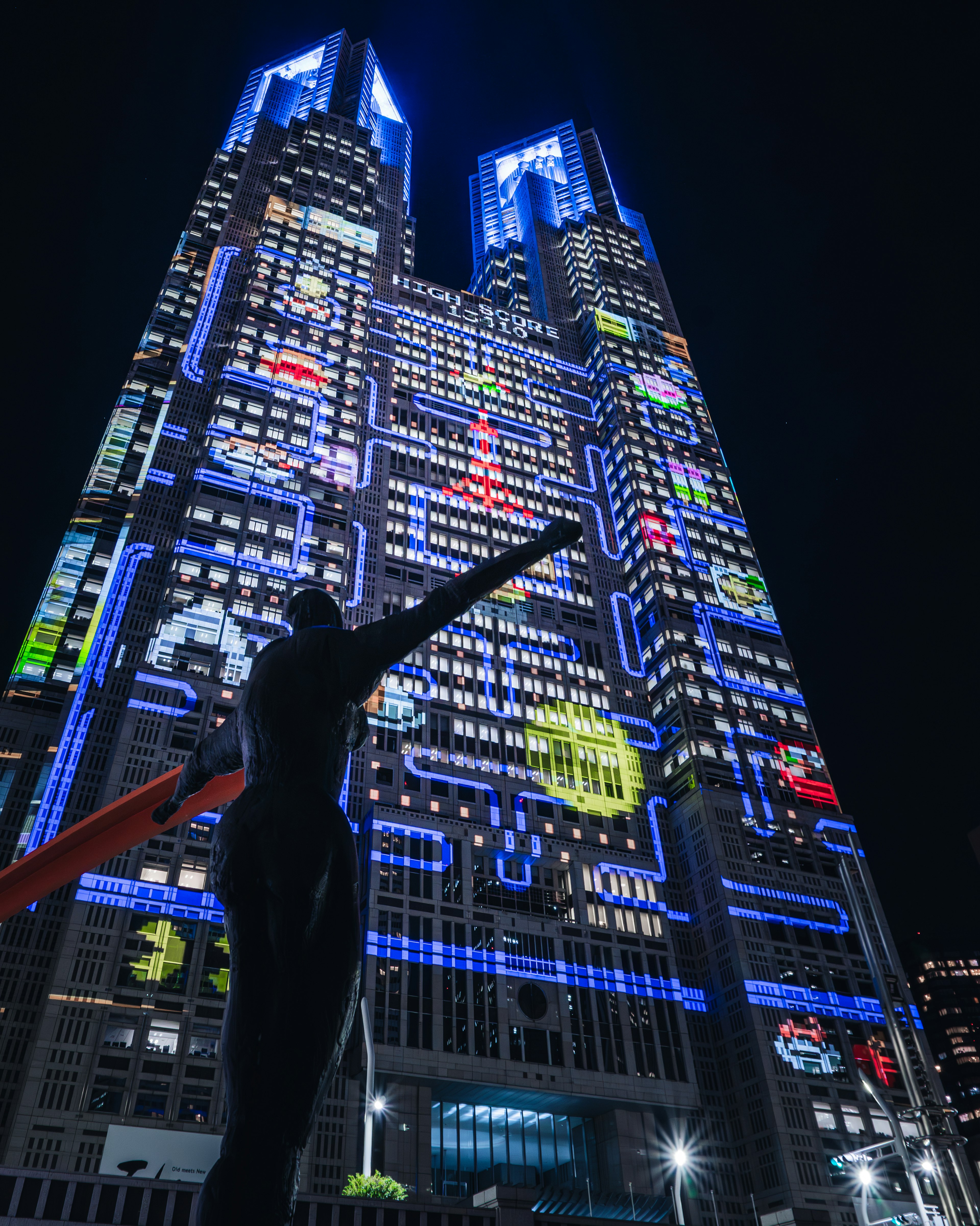 Estatua frente a un edificio iluminado con pantallas LED coloridas de noche