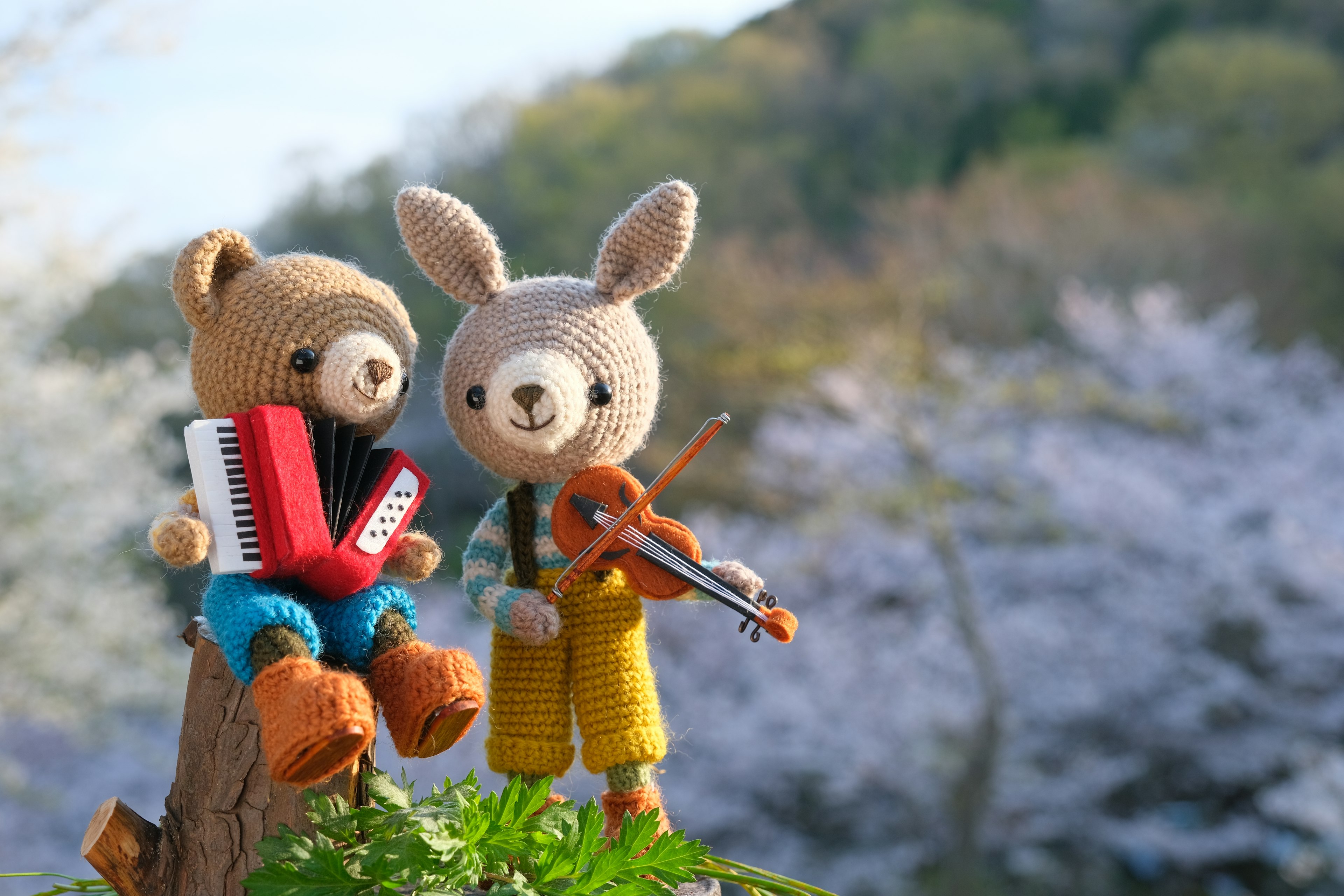 A bear and a rabbit plush playing music in a scenic background