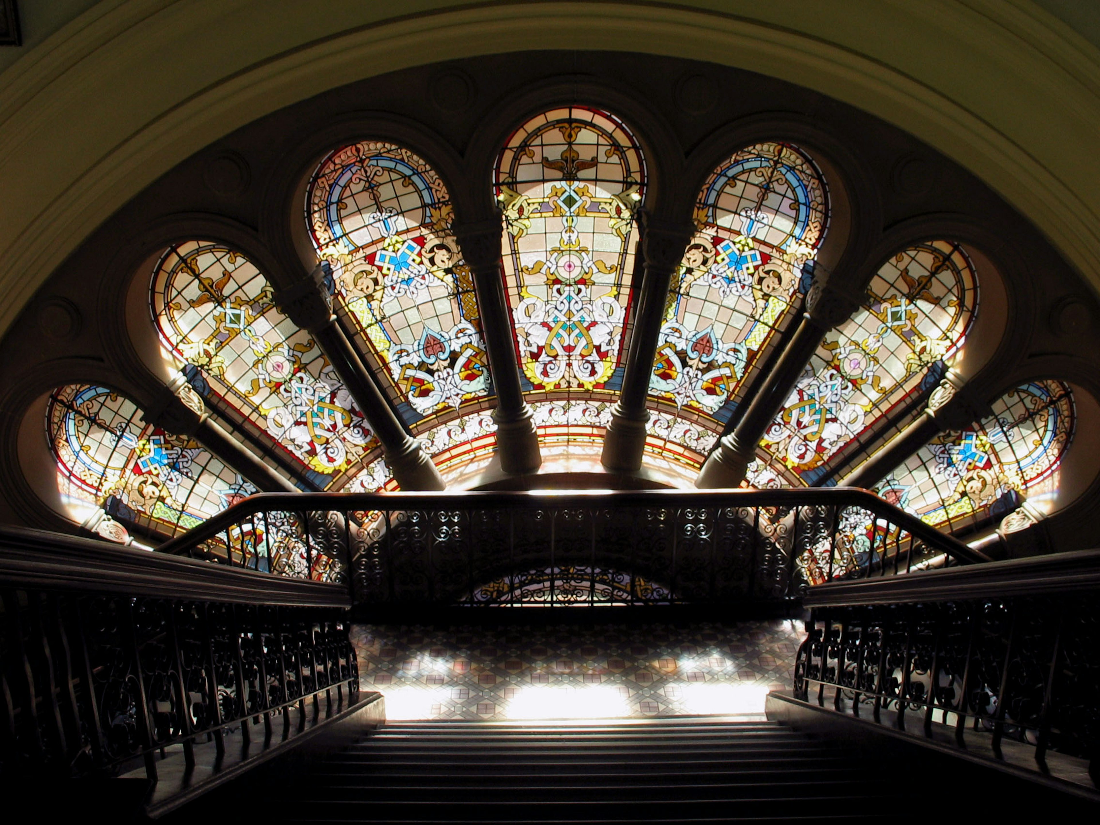 Hermosas ventanas de vitrales arqueadas sobre una escalera