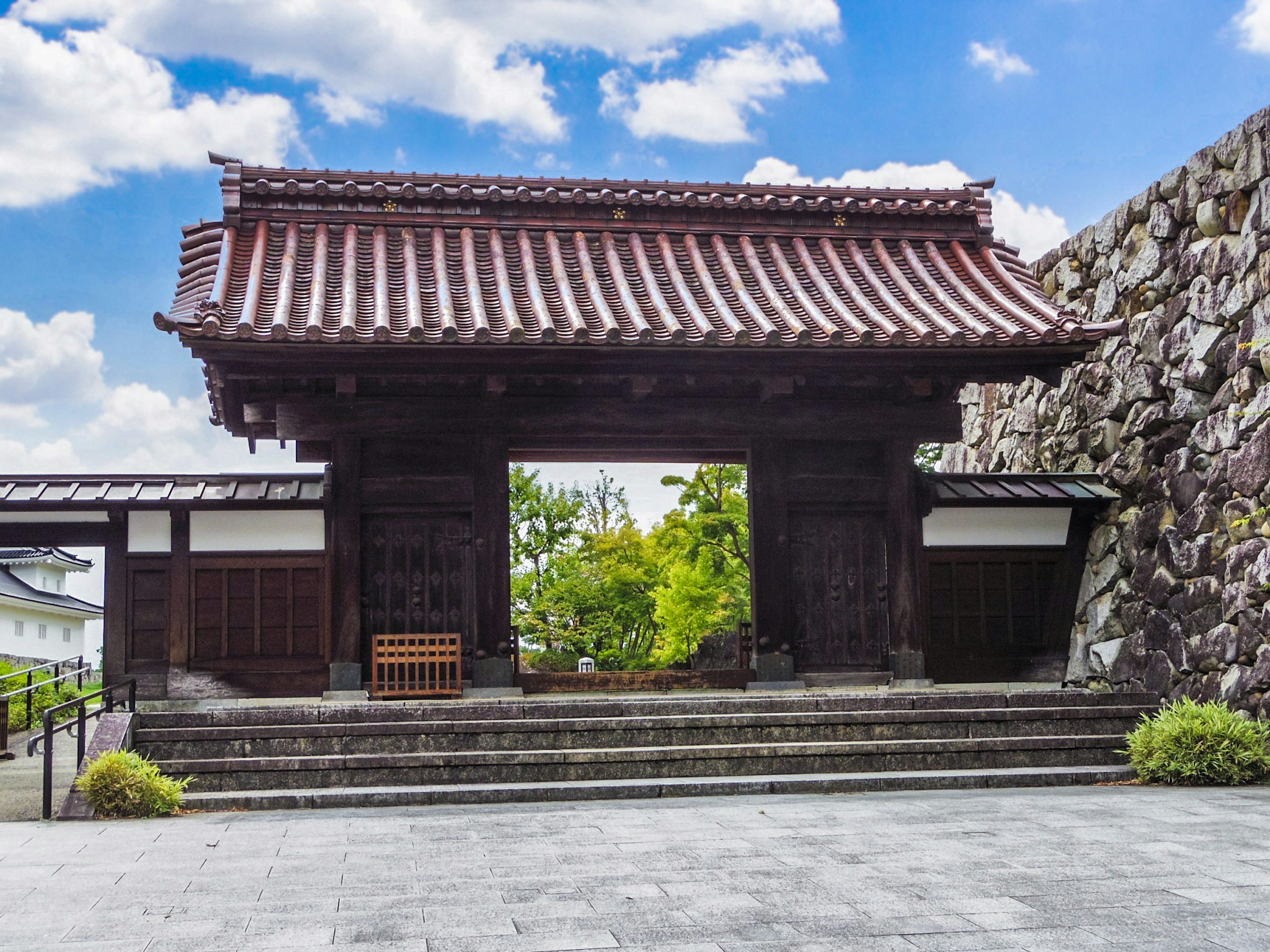 Traditional gate with a red roof and stone wall in a scenic view