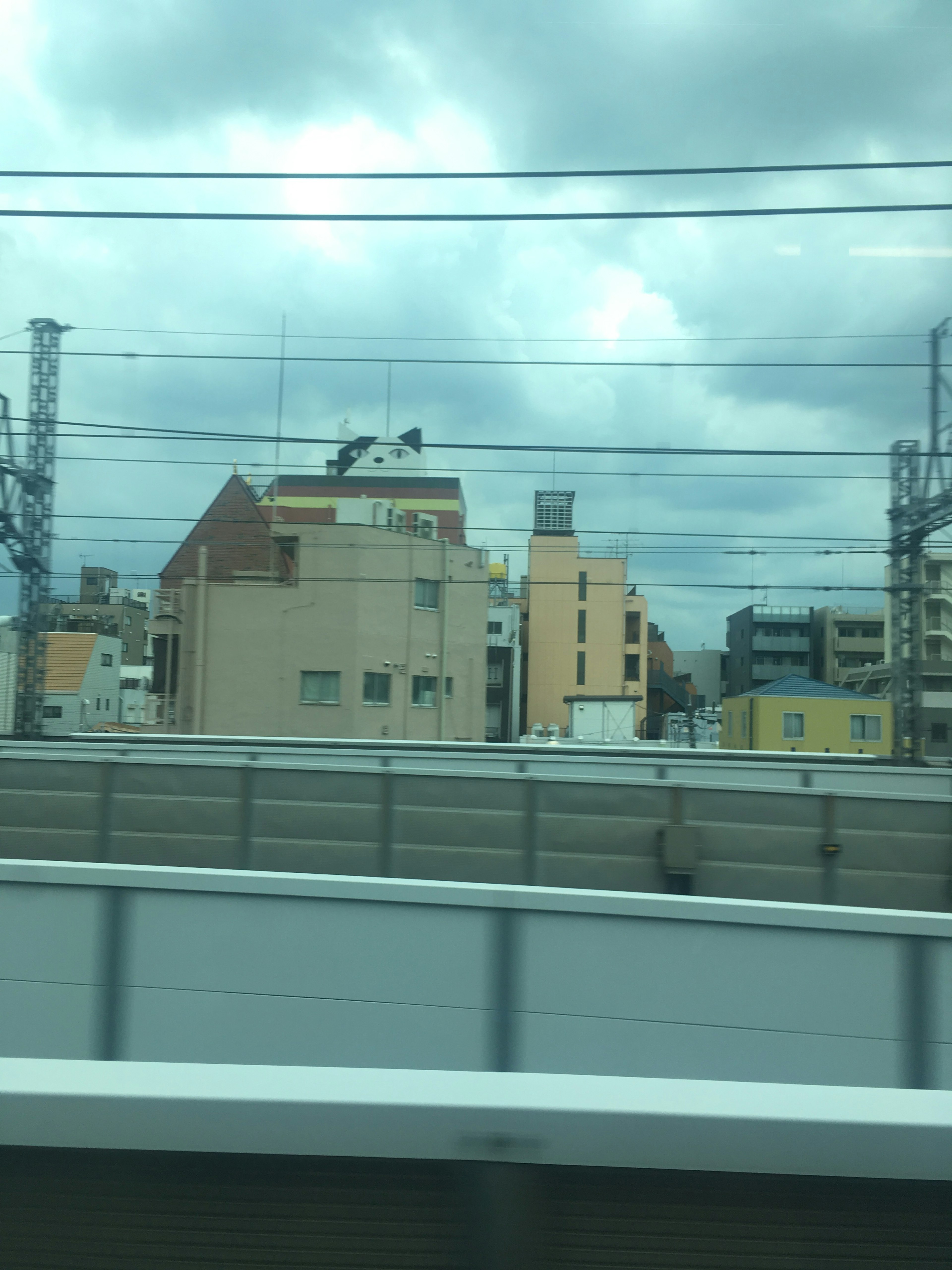 Urban landscape viewed from a train featuring tall buildings and power lines