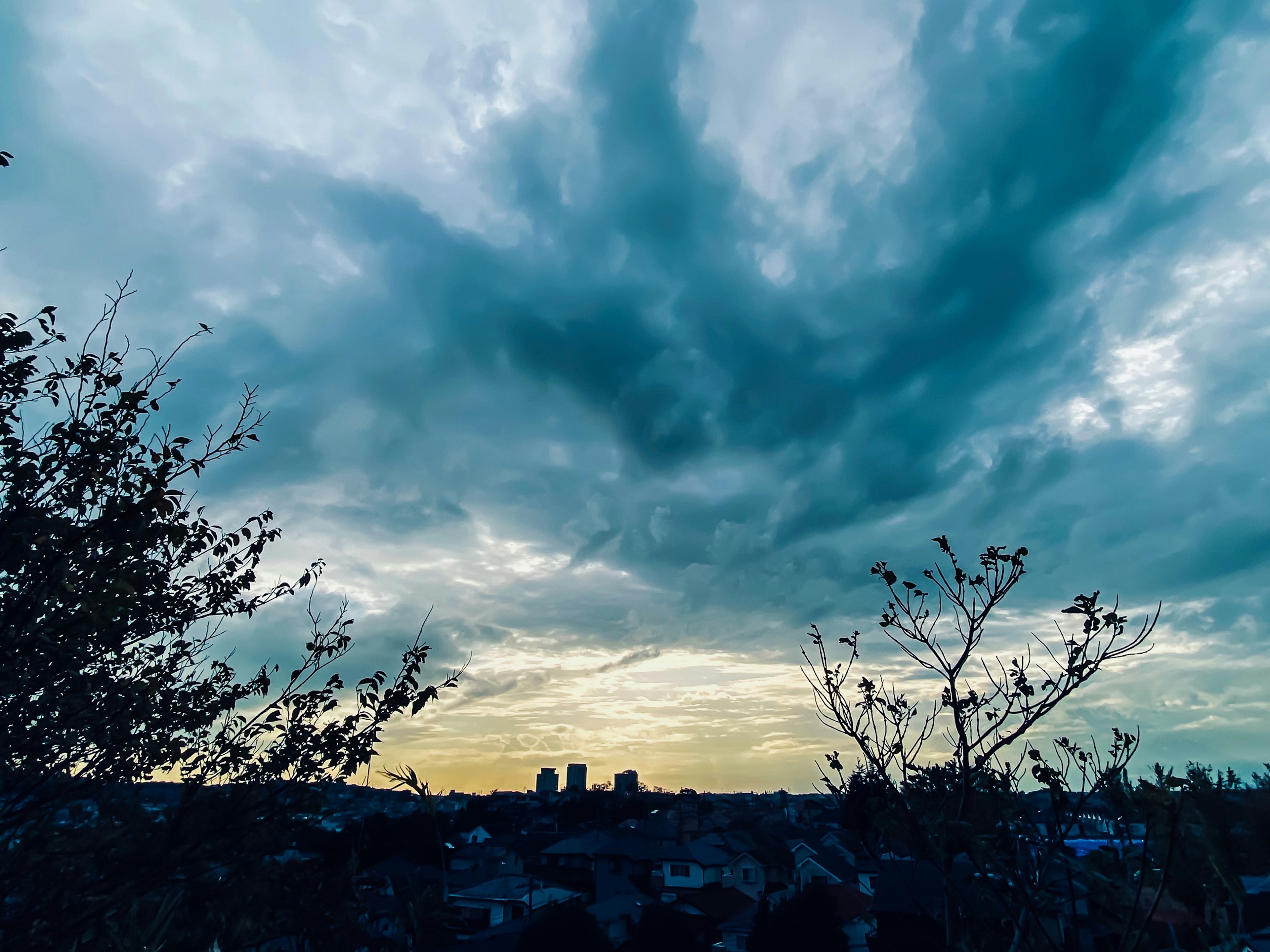 Siluet bangunan melawan langit senja dramatis yang dipenuhi awan