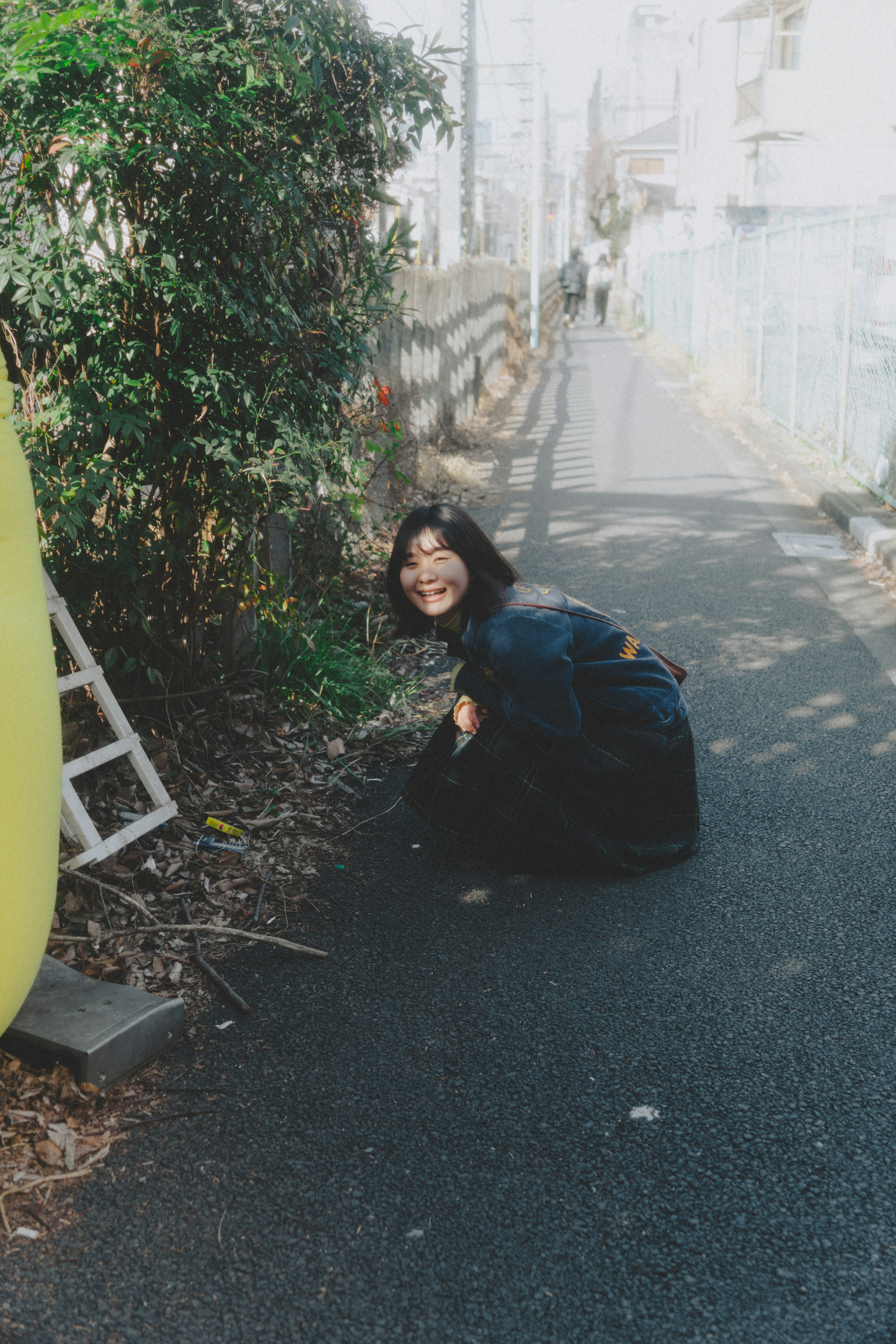 A woman squatting on the roadside smiling