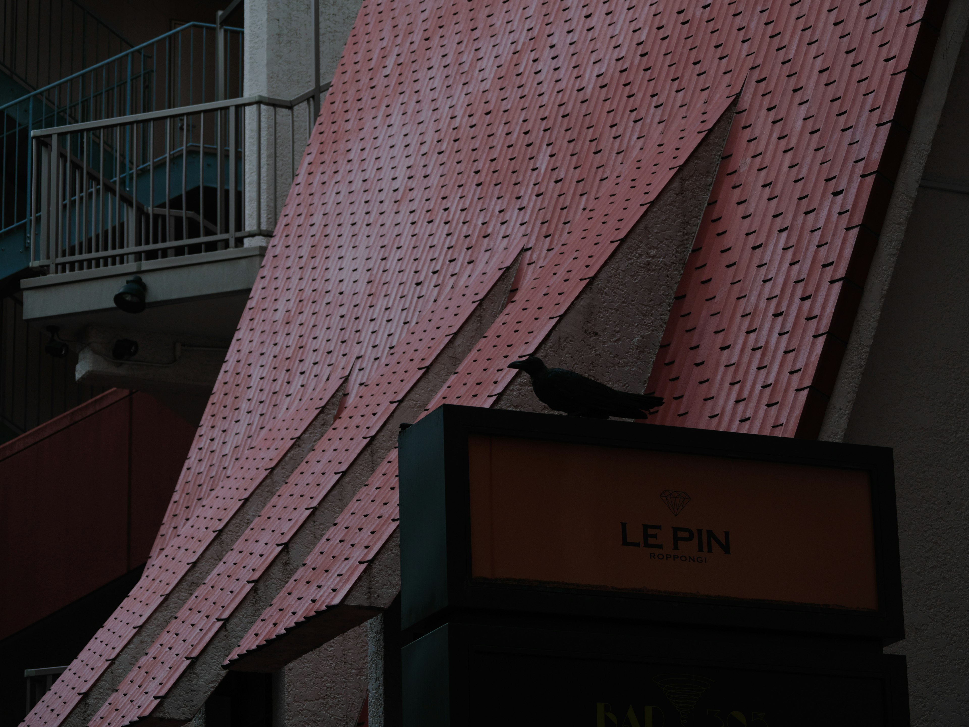 A black bird perched on a structure with sharp pink design elements