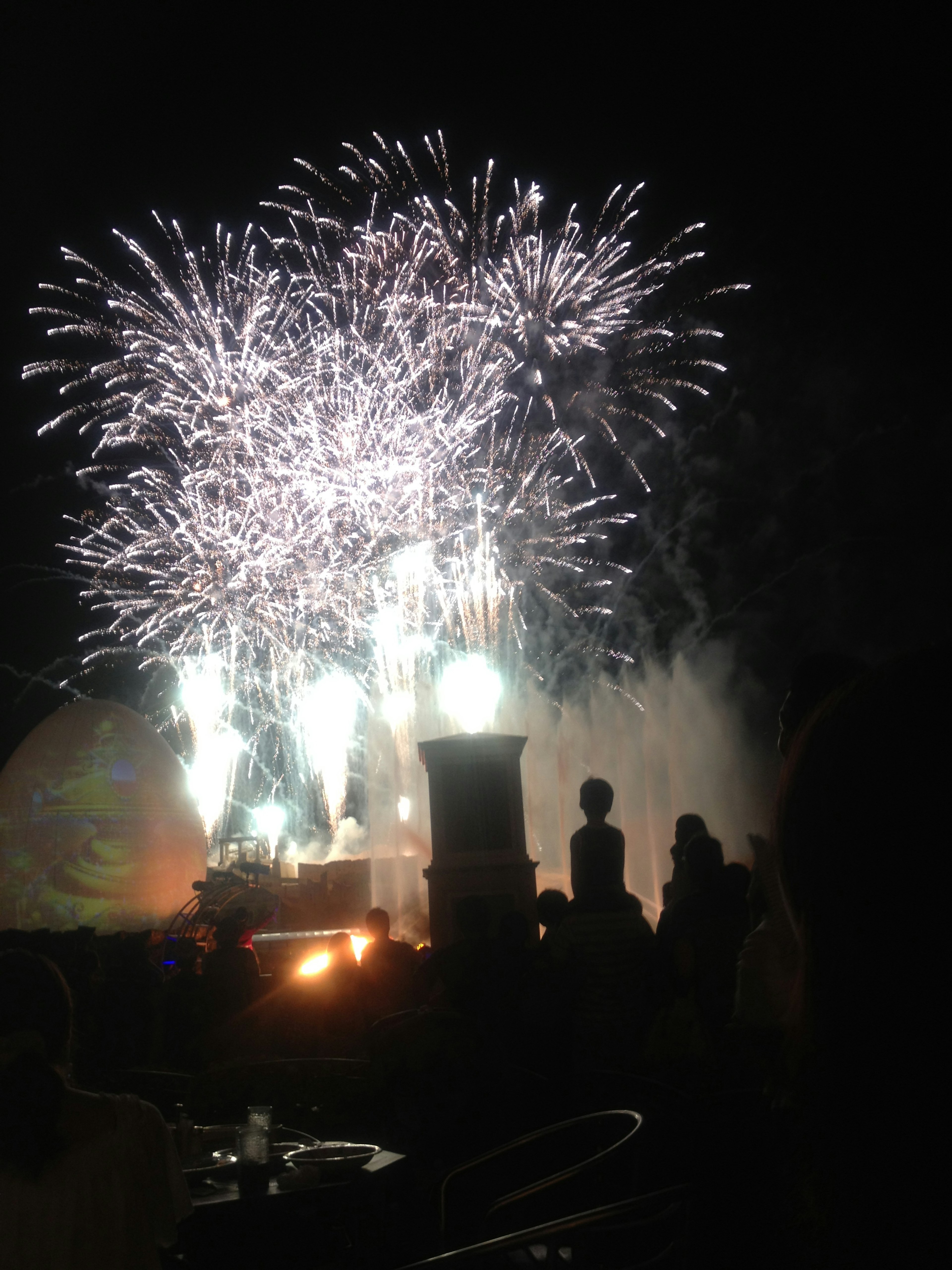 夜空に輝く花火とシルエットの人々