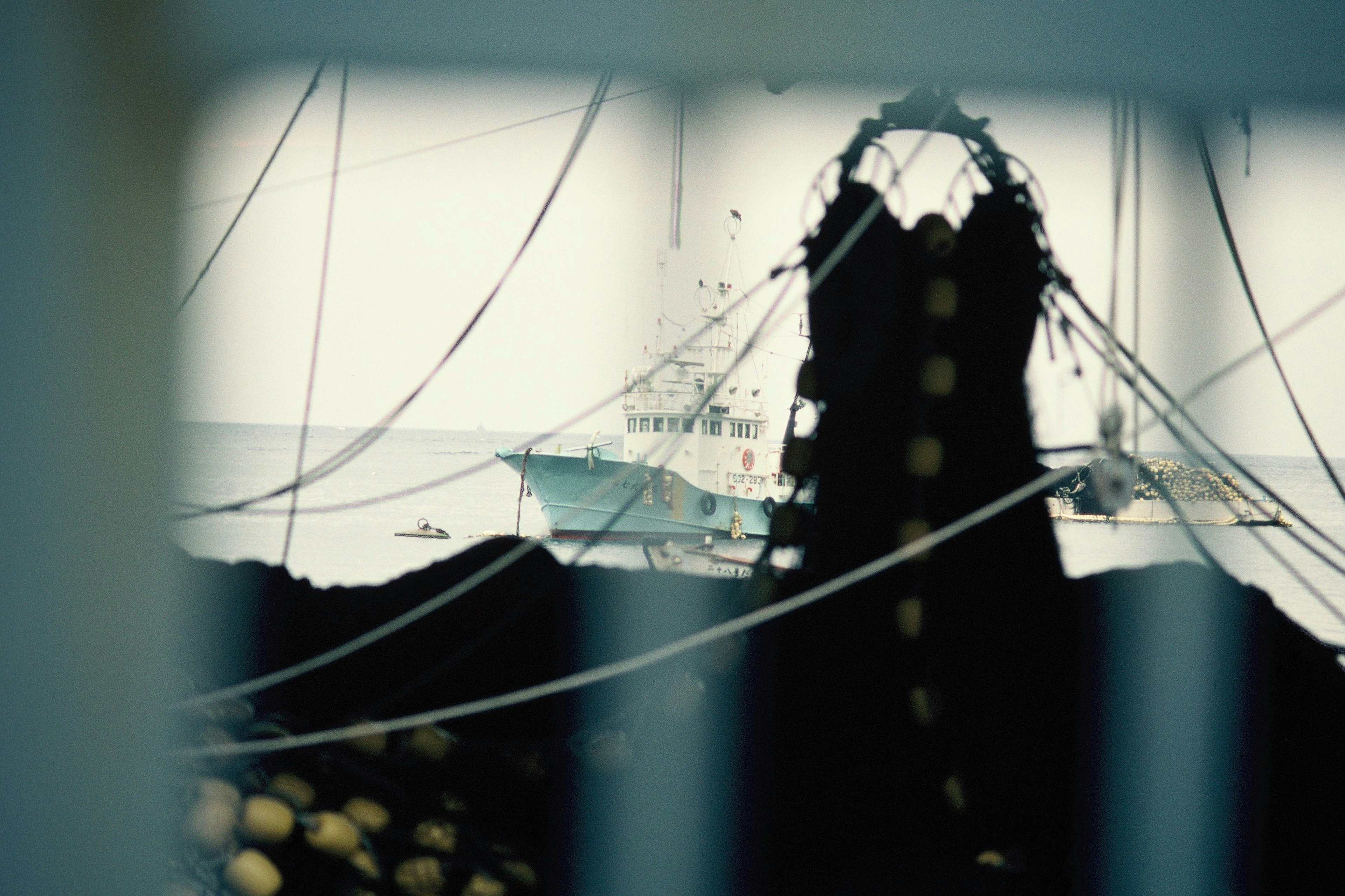 Silhouette of fishing nets with a boat and the sea in the background