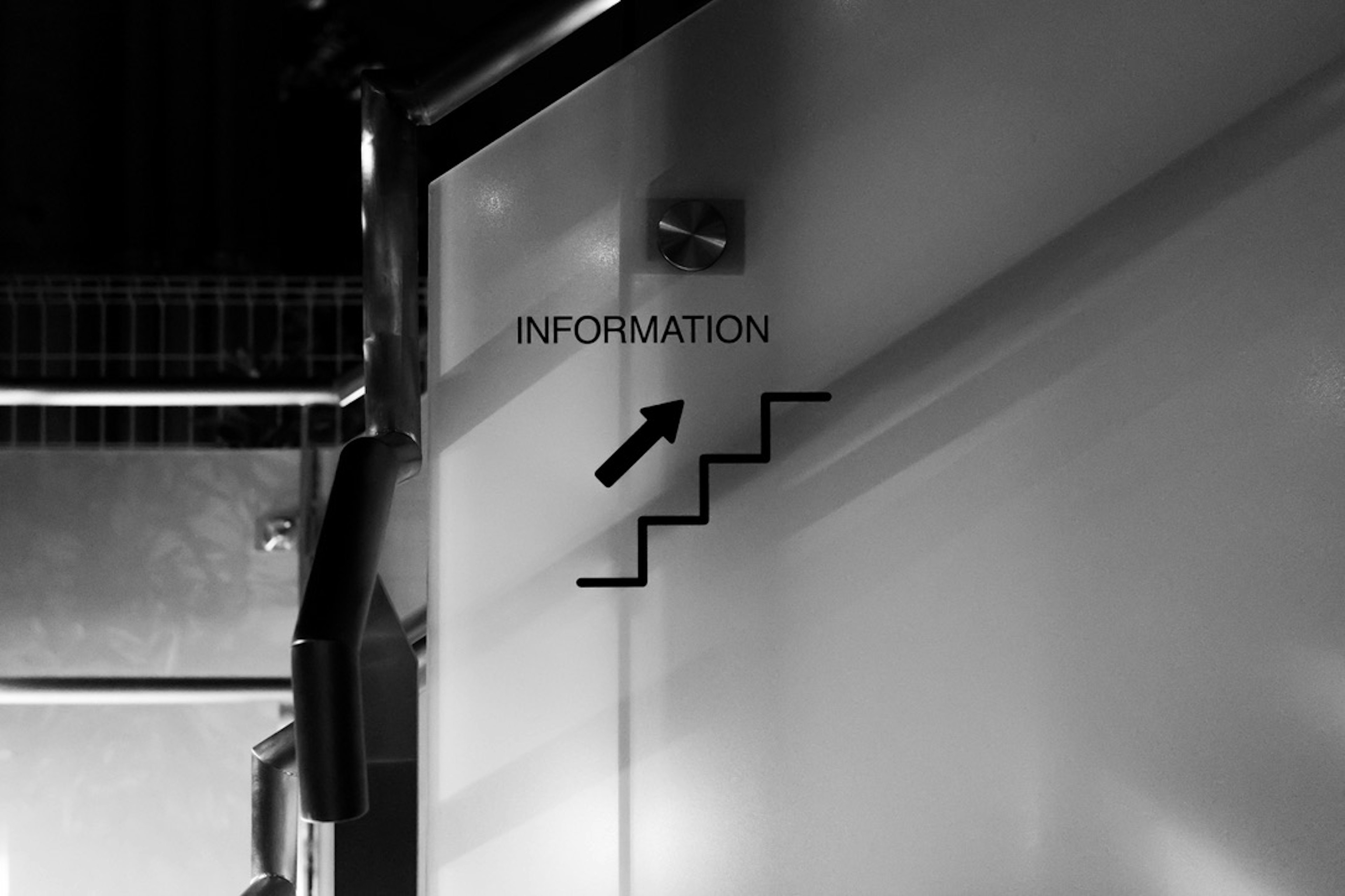 Black and white wall with information sign and arrow pointing to stairs