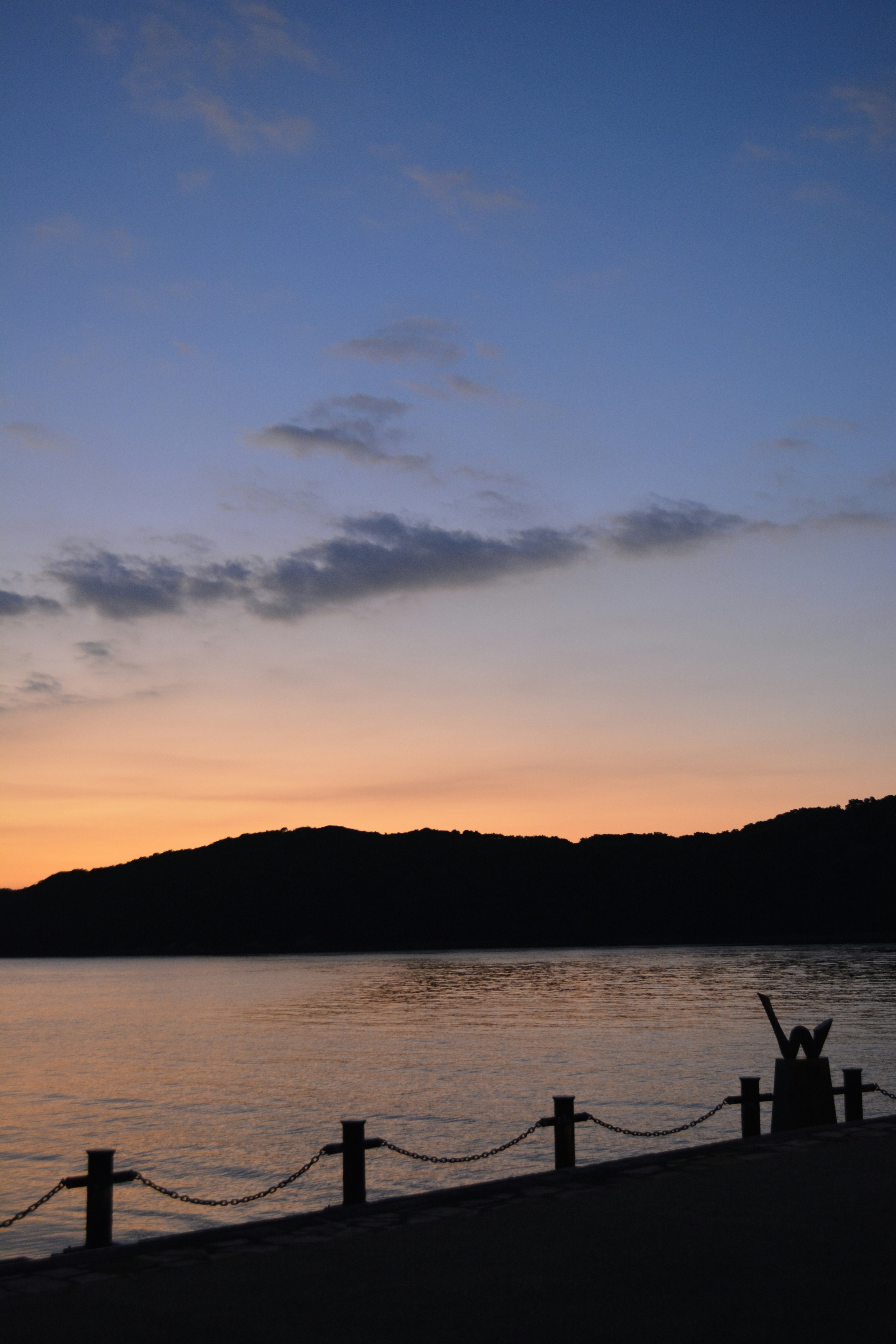 夕焼けの海辺でシルエットの人々が楽しんでいる風景