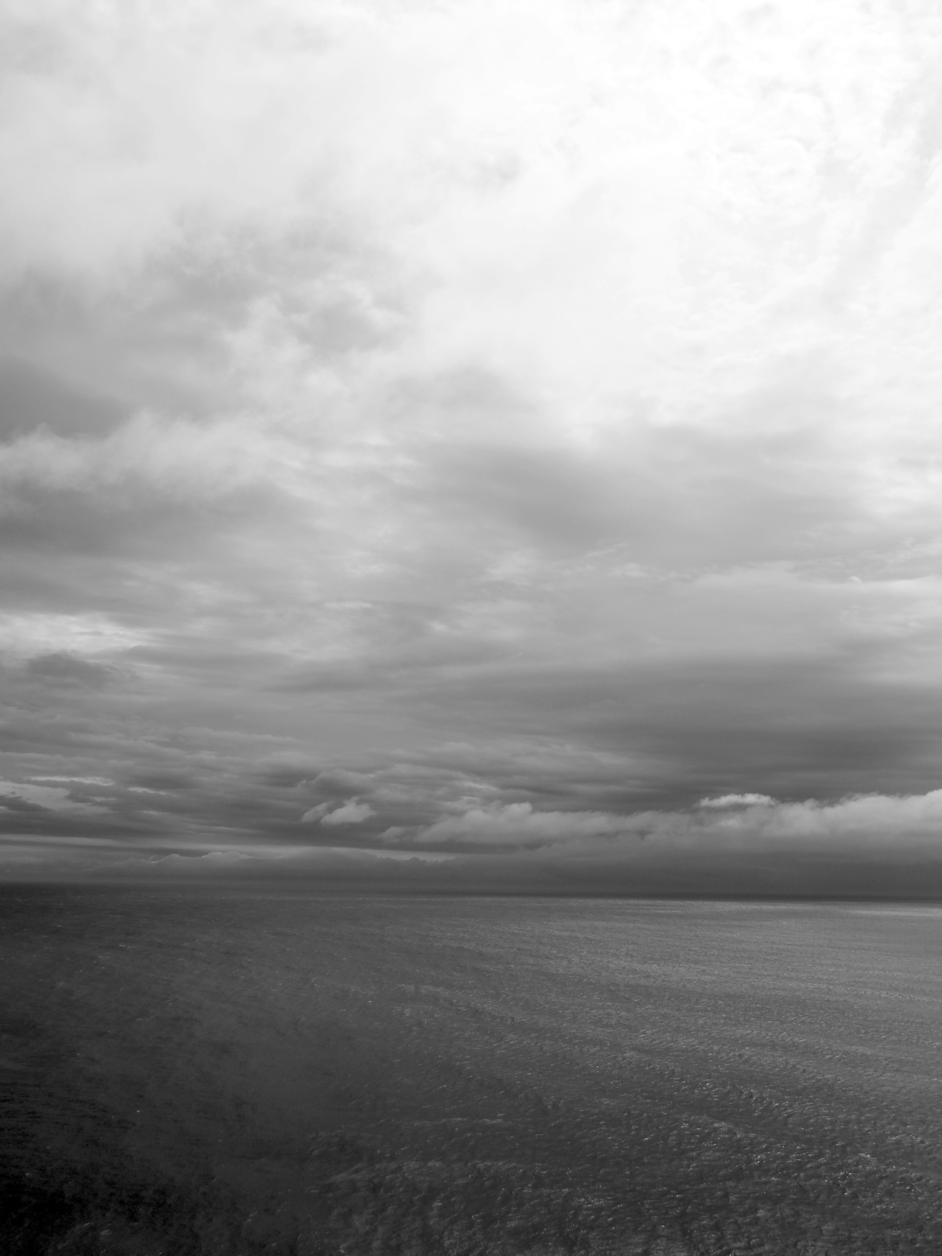 Black and white image of vast sea and cloudy sky