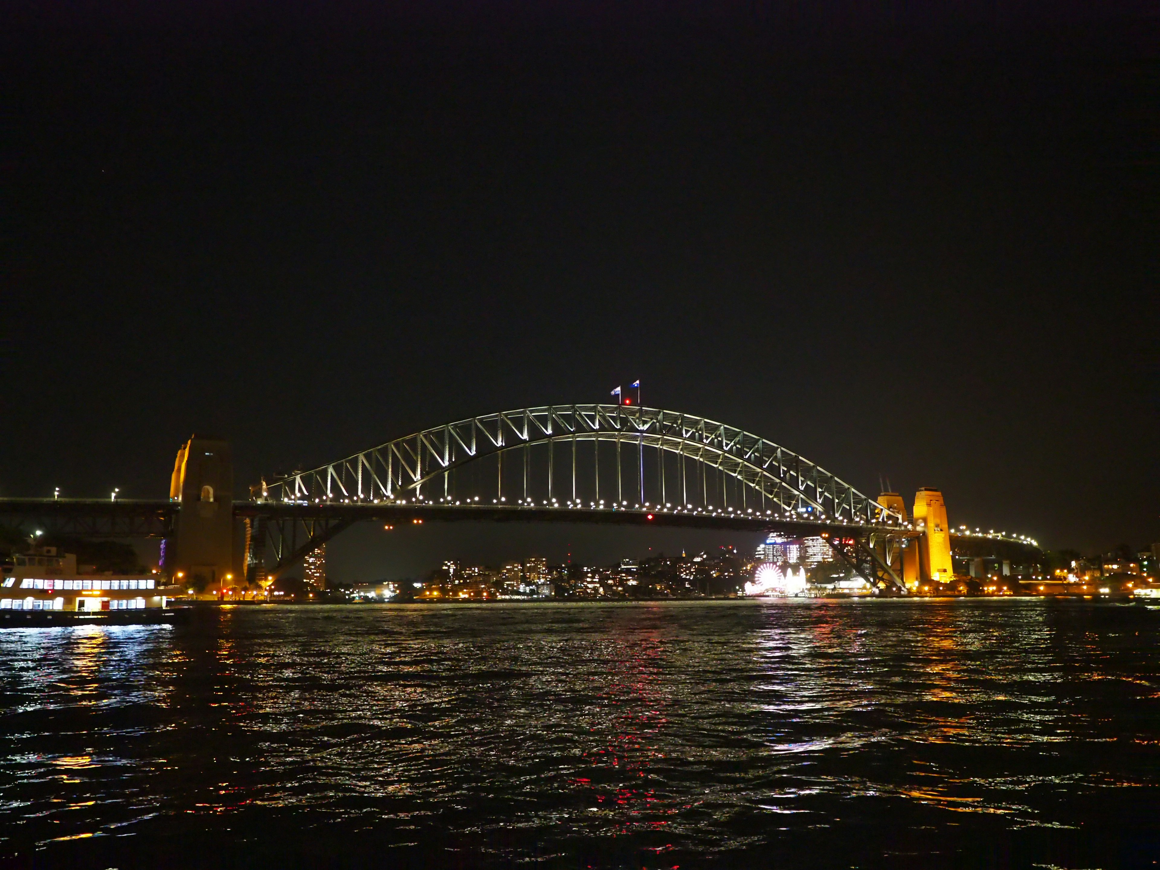 Hermosa vista del puente de la bahía de Sídney por la noche con reflejos en el agua