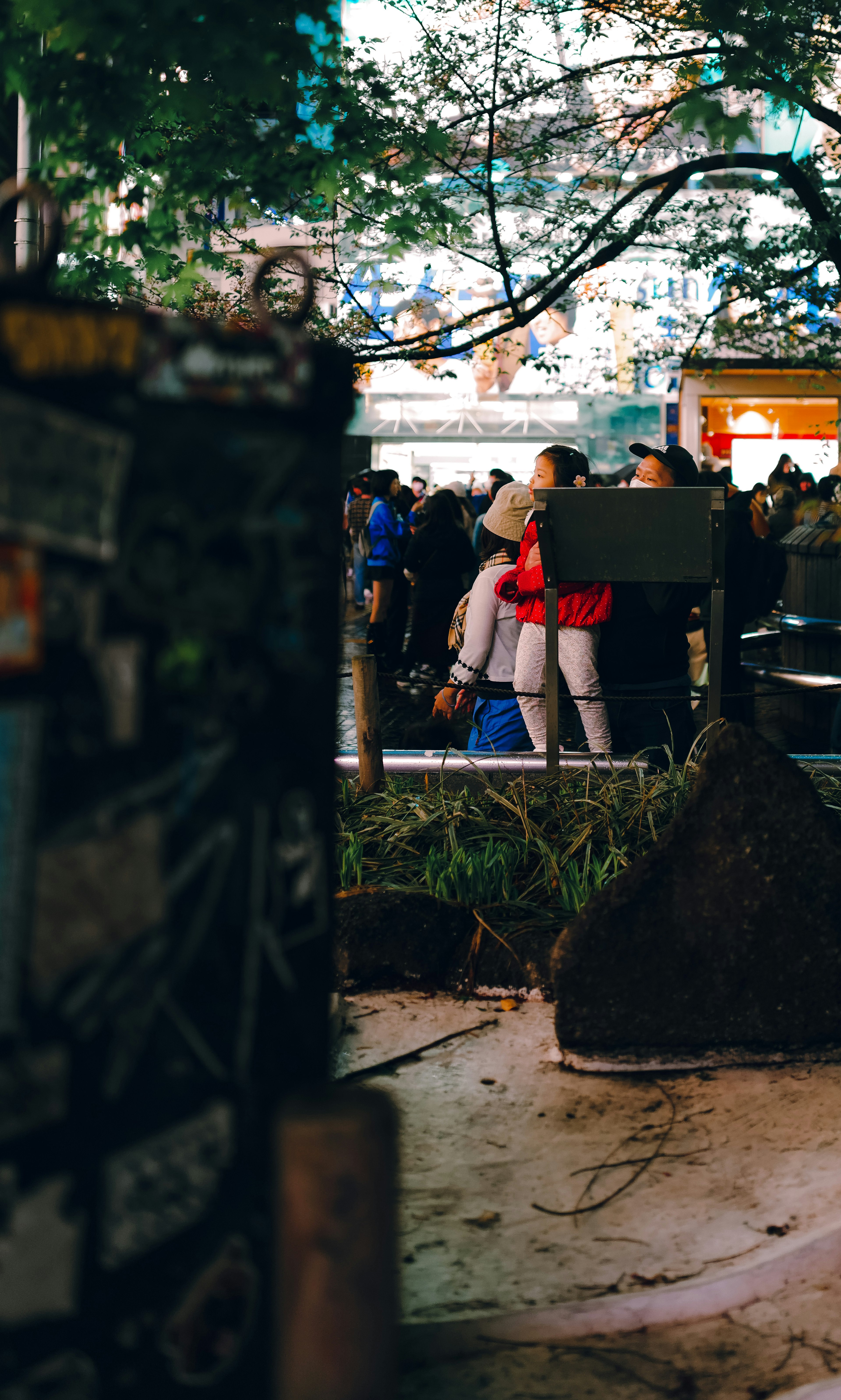 Couple embracing in a bustling urban night scene with people in the background