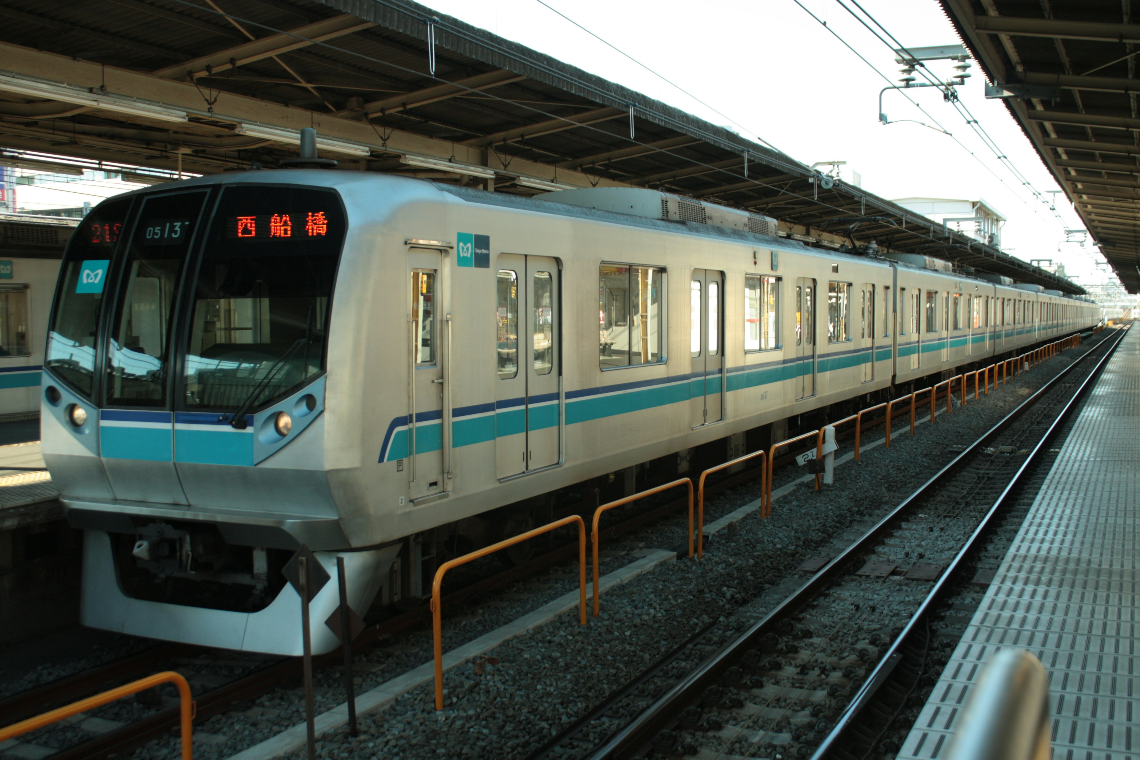 Train blanc avec des rayures bleues arrêté sur un quai de gare