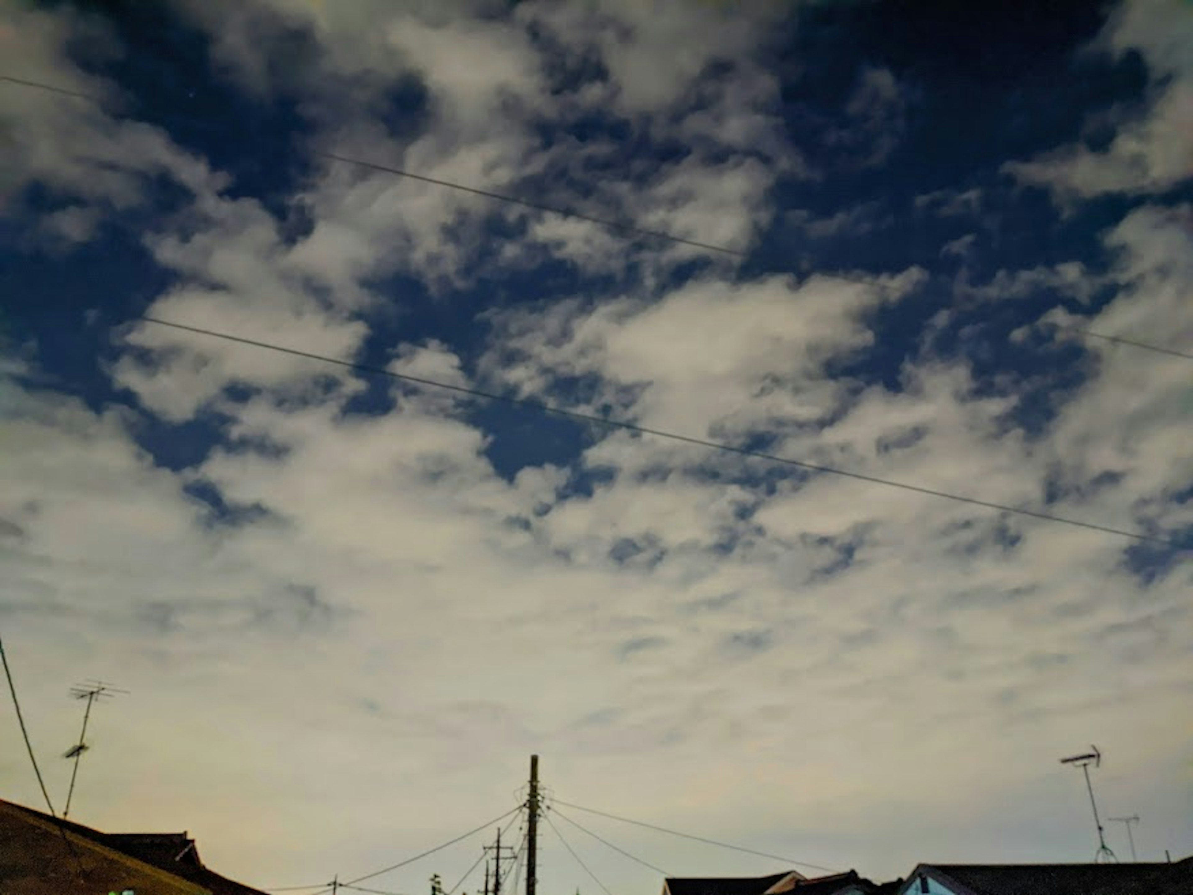 青空に浮かぶ白い雲と電線が見える風景