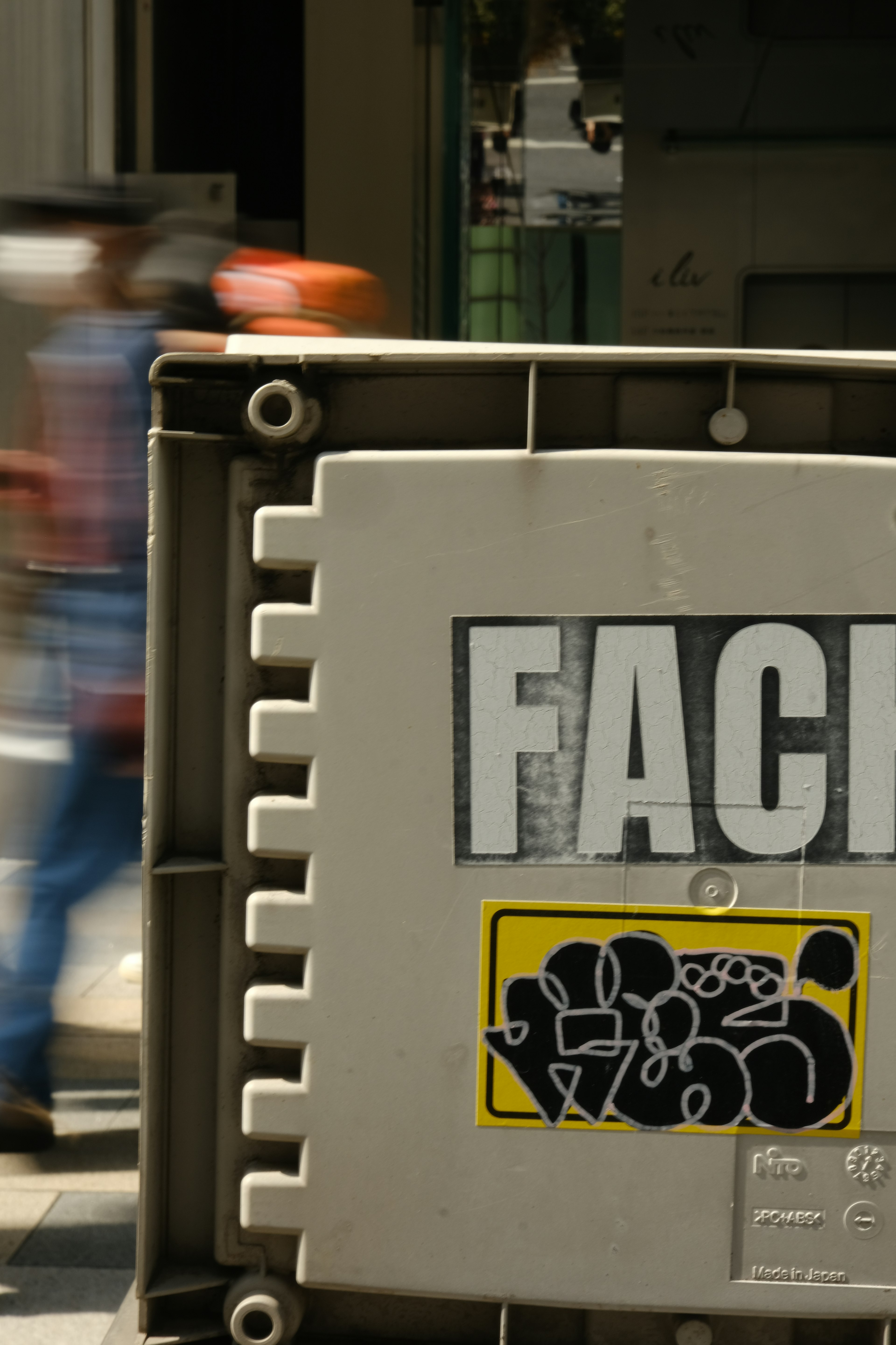 Graffiti-covered box in a busy street with blurred pedestrians